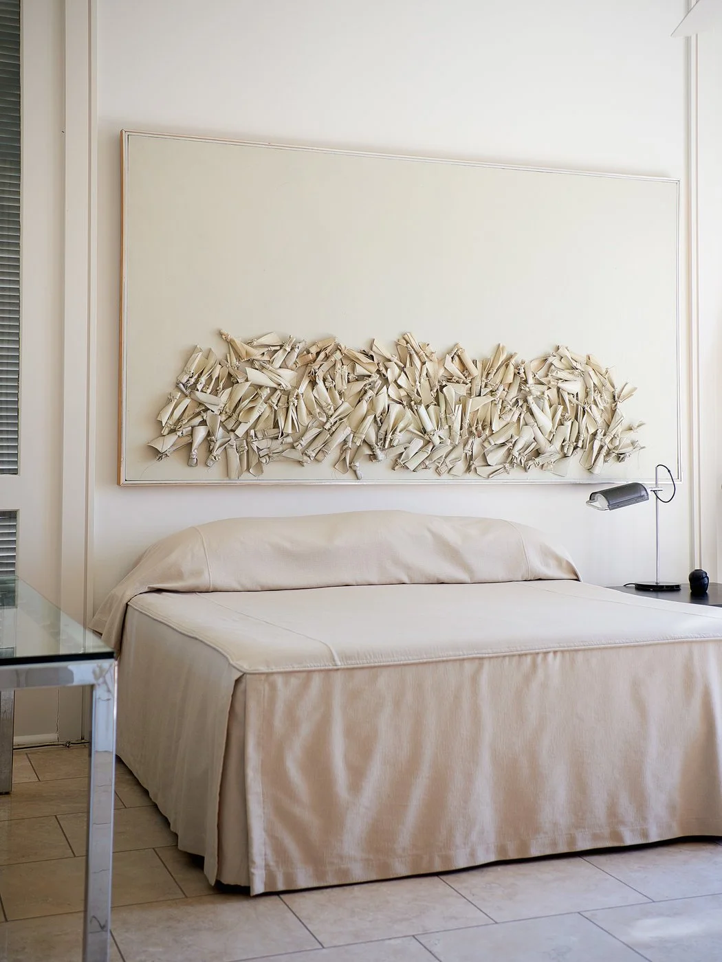 A nine-foot-long painting from Dunbar’s 1984 Rag Series collection hangs above his bed. Credit Paul Costello