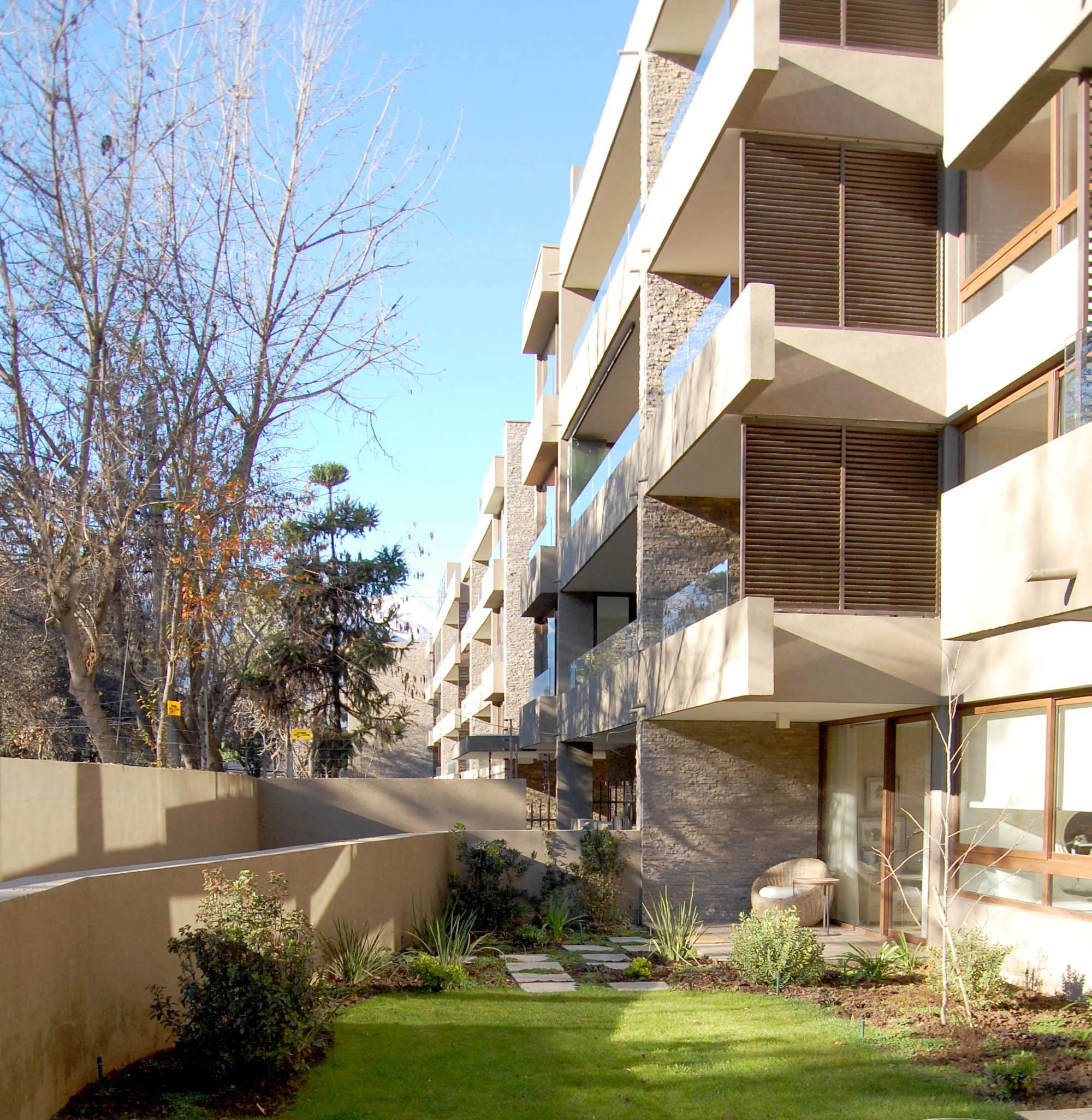 En un terreno de 5.424,23 m2, frente a la plaza Los Espinos con un fuerte caracter residencial y un frente de 115 m hacia la calle EL Espino. El conjunto de dos edificios de 64 dptos totales se emplaza en el terreno buscando dejar patios de uso exclusivo para los deptos en primer piso, generando ricones y lugares singulares. La presencia de los arboles y su corteza marrón grisasea fueron la inspiración para los colores y texturas del conjunto. Por otro lado se optó por cocinas integradas para departamentos de 140 m2, por lo que se uso un diseño moderno y sobrio.