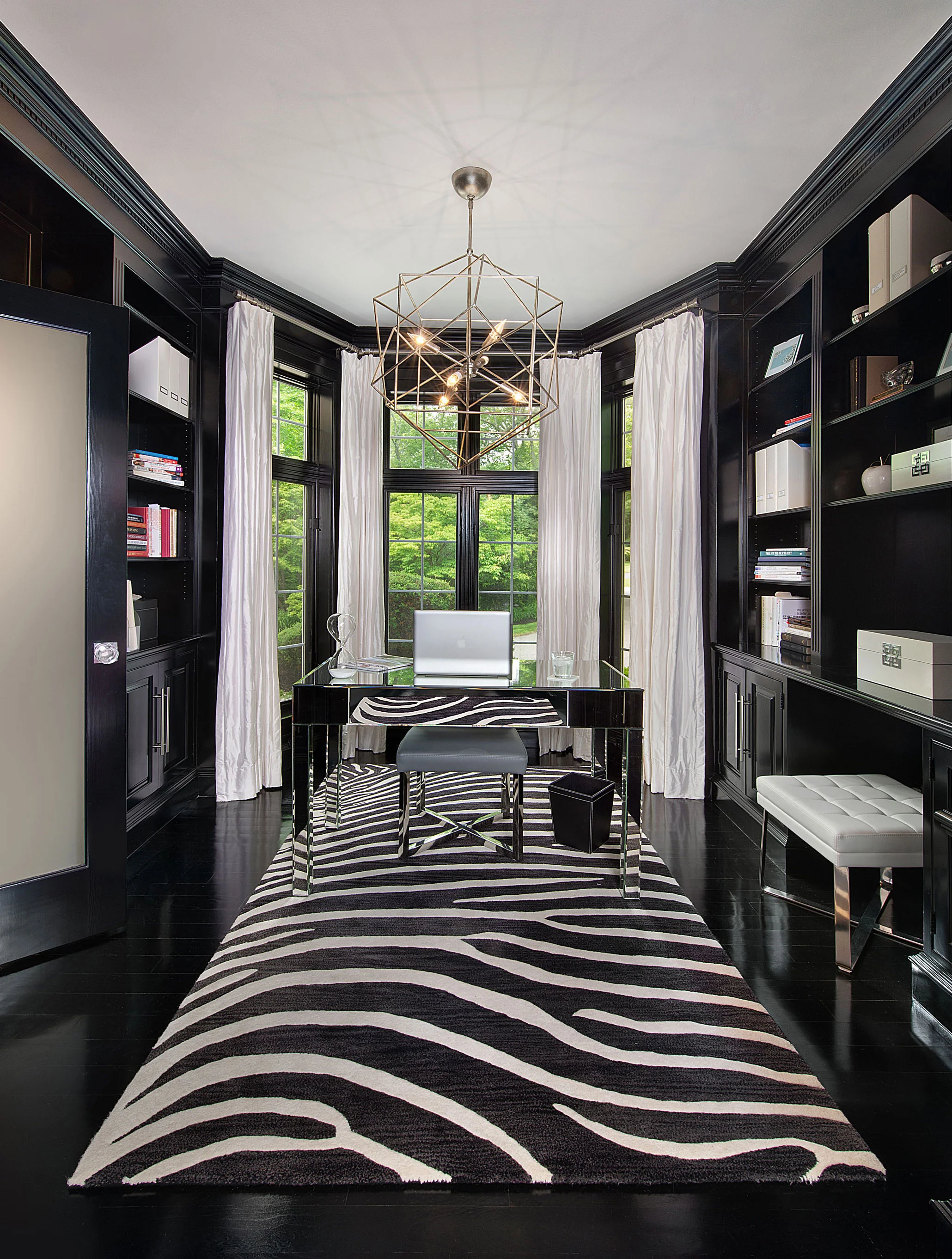 The adjoining library is a reverse of color. High gloss black trim with white accents make for a striking room.