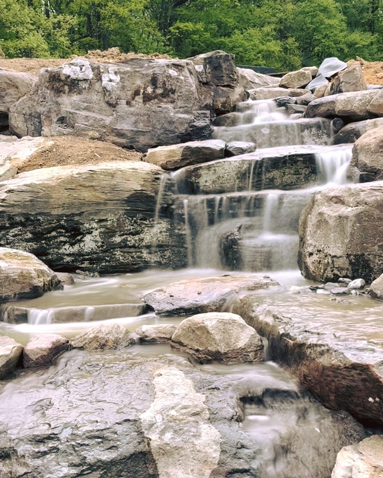 She&rsquo;s ALIVE. 💦
20,000 gallons per hour cascading over 10+ feet of natural boulder work &mdash; and we&rsquo;re just getting started. Yes, the water is still dirty and there&rsquo;s finish work ahead, but we fired up the falls to test the flow,
