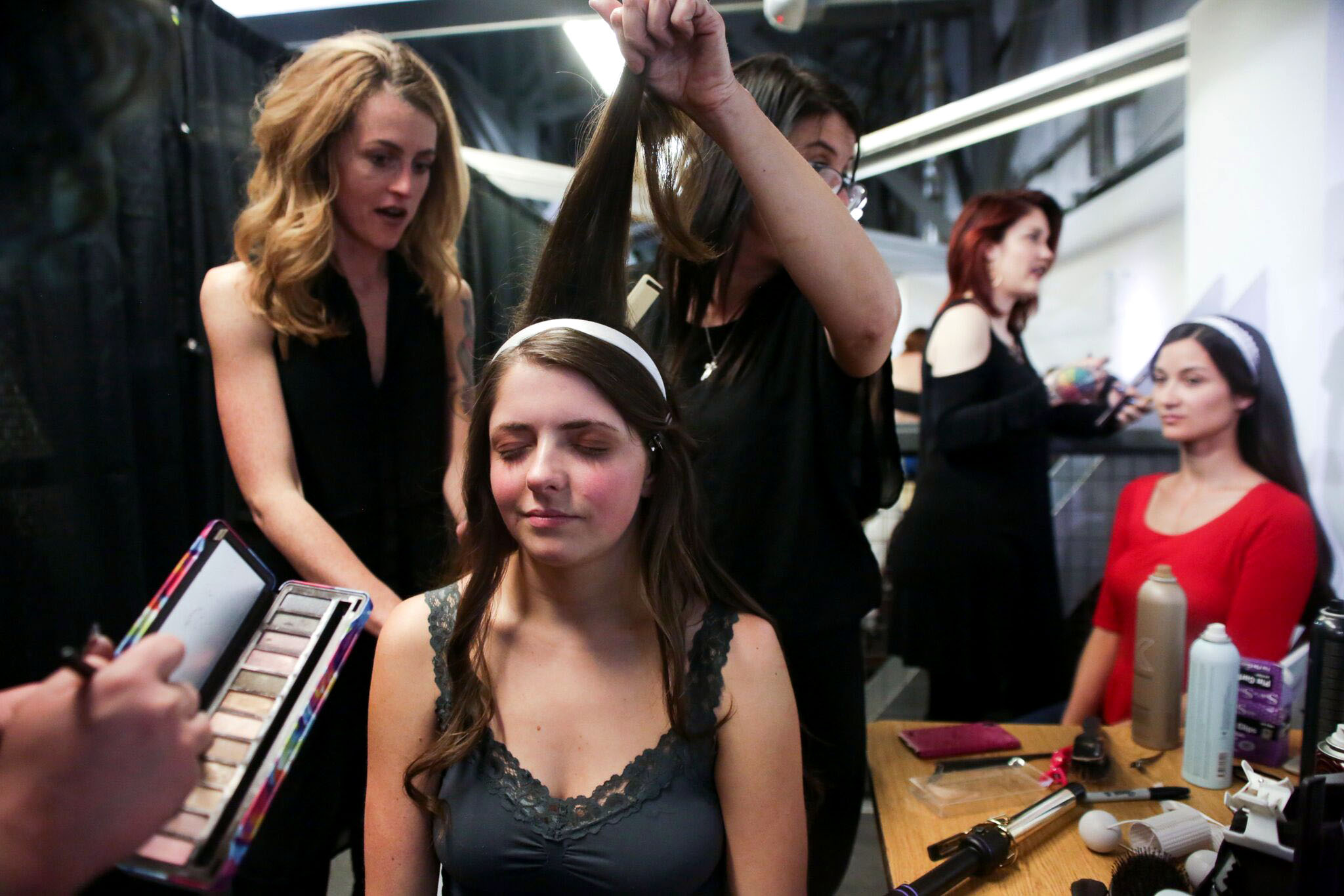 Makeup artists and hairstylists get a model ready for the runway during Denver Fashion Week on March 18, 2018 at Wings Over the Rockies Air and Space Museum in Denver, Colorado.
