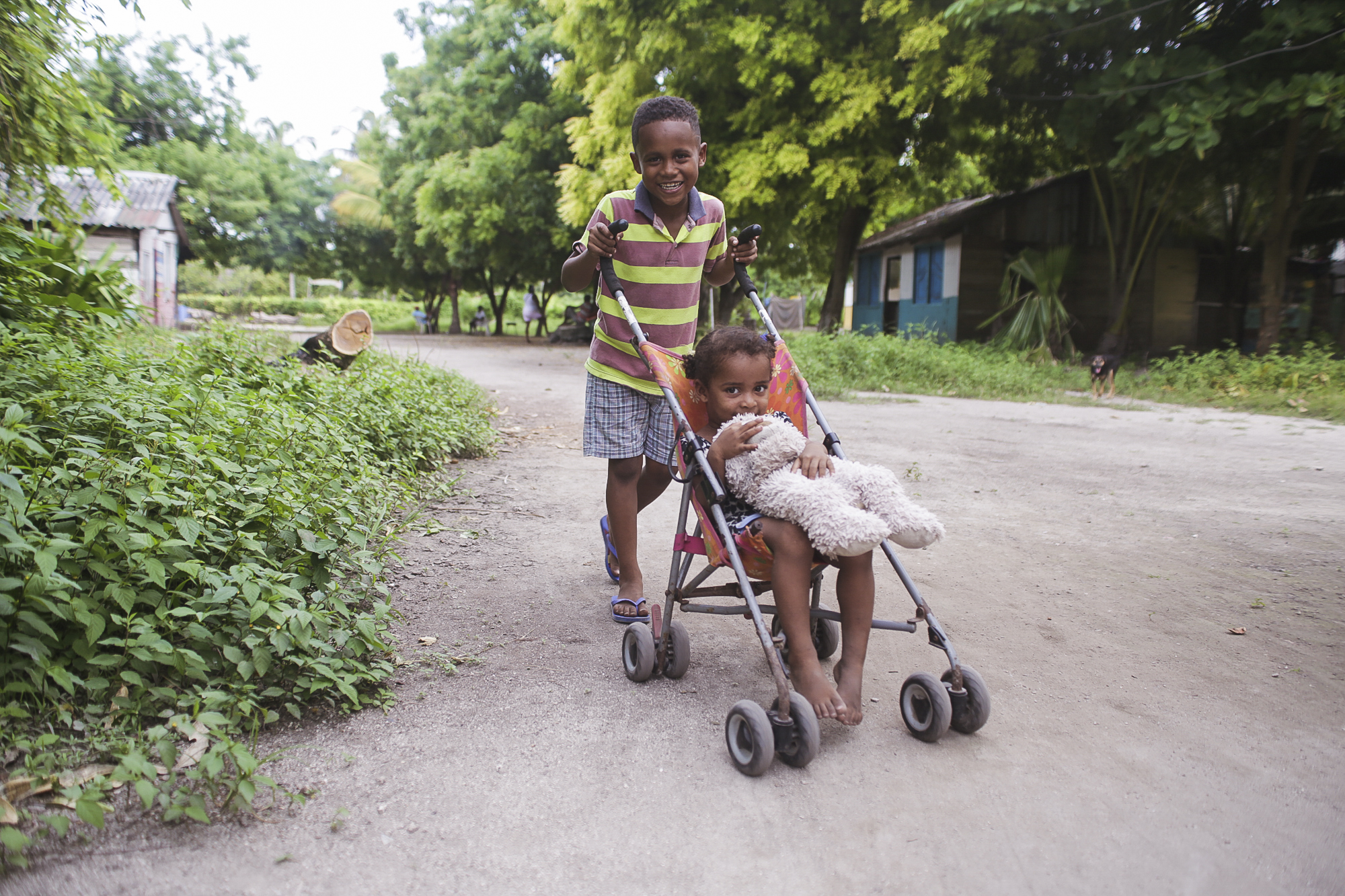 A little boy pushes his sister in a stroller around the Rosario Islands in Colombia on July, 10 2018. These kids were being playful and seeing how fast they could go around this dirt path.