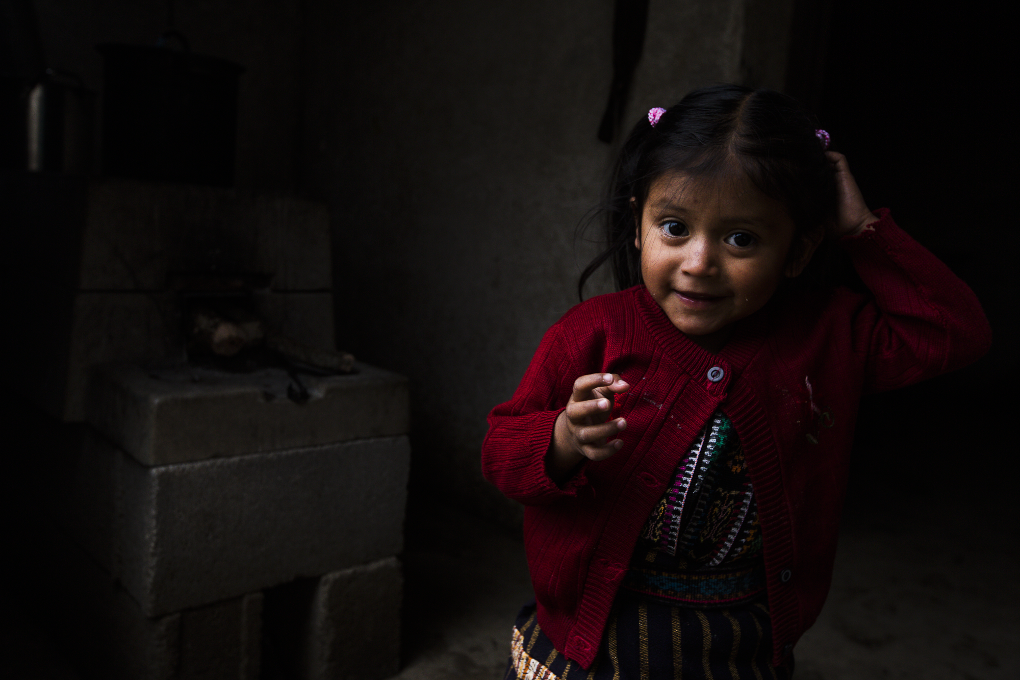 A little girl plays outside of her house with her family in Peña Blanca, Guatemala.