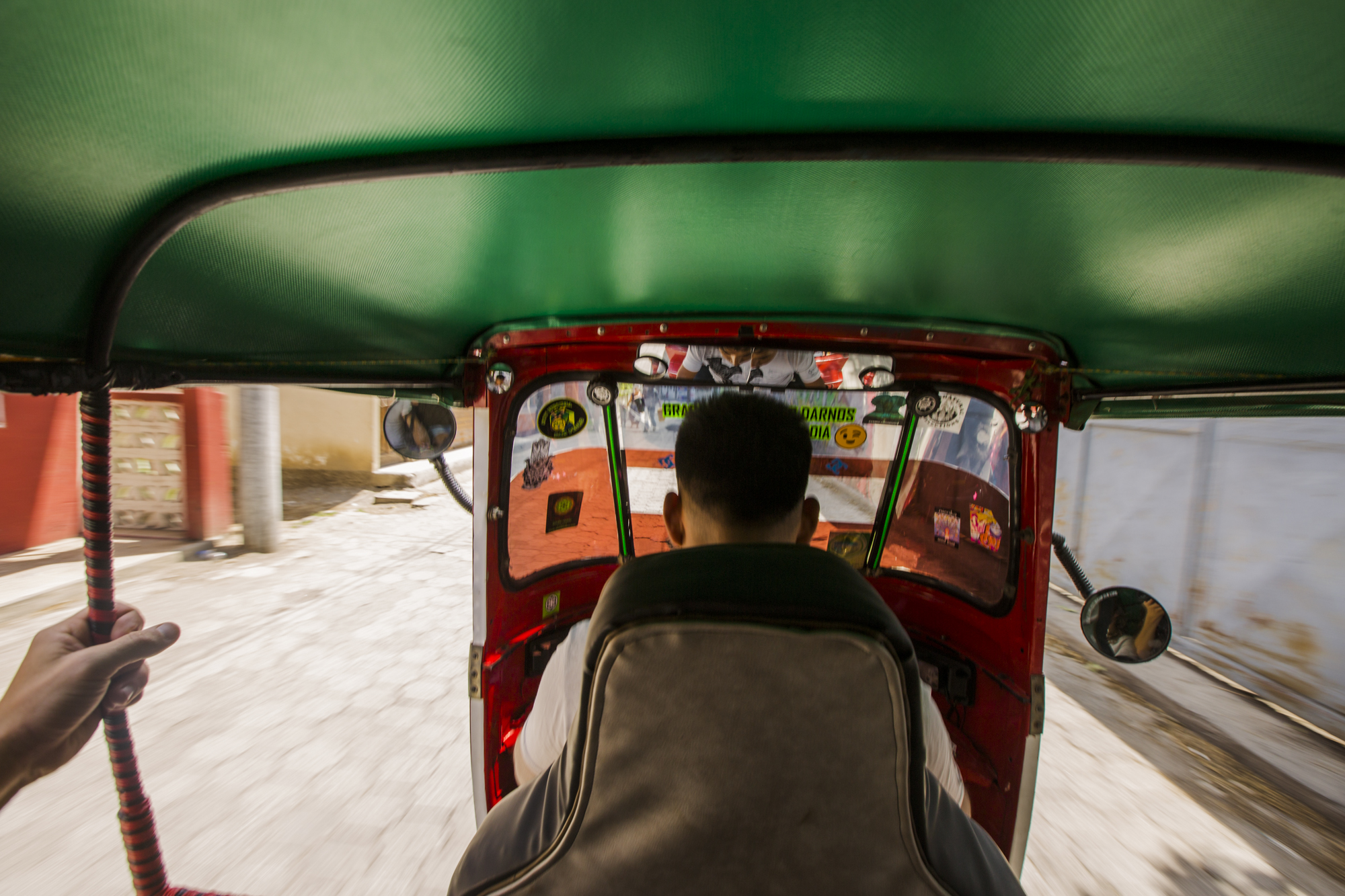View from the back of a tuk tuk in San Pedro La Laguna, Guatemala. Tuk tuks are a common form of transportation in Guatemala. They are very convenient as they can be found on almost every street and they can fit through small alleyways.