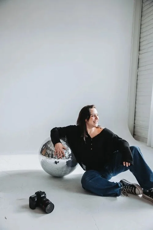 professional brand photographer sitting with camera and disco ball, demonstrating visual storytelling strategy