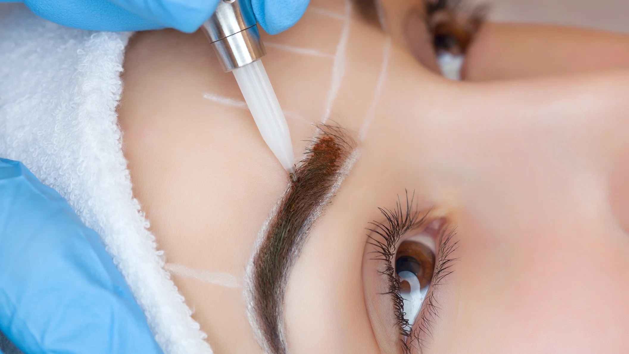 A microblading tech fills in a client’s brow