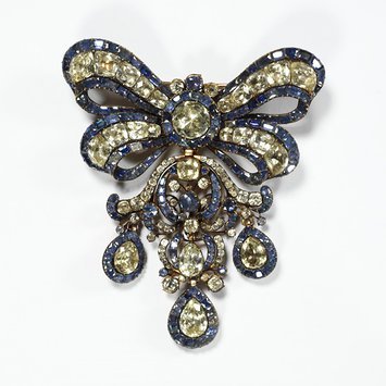 Girandole bow bodice ornament and pair of earrings set with topazes,backed with foil, and sapphires. All the stones are set in gold. Circa 1760, France V&A Museum