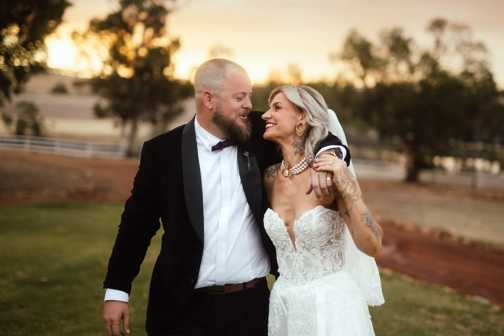 A romantic golden hour portrait of a bride and groom walking together at Buckland Estate, captured by a luxury Perth wedding photographer against a soft, glowing outback sunset.