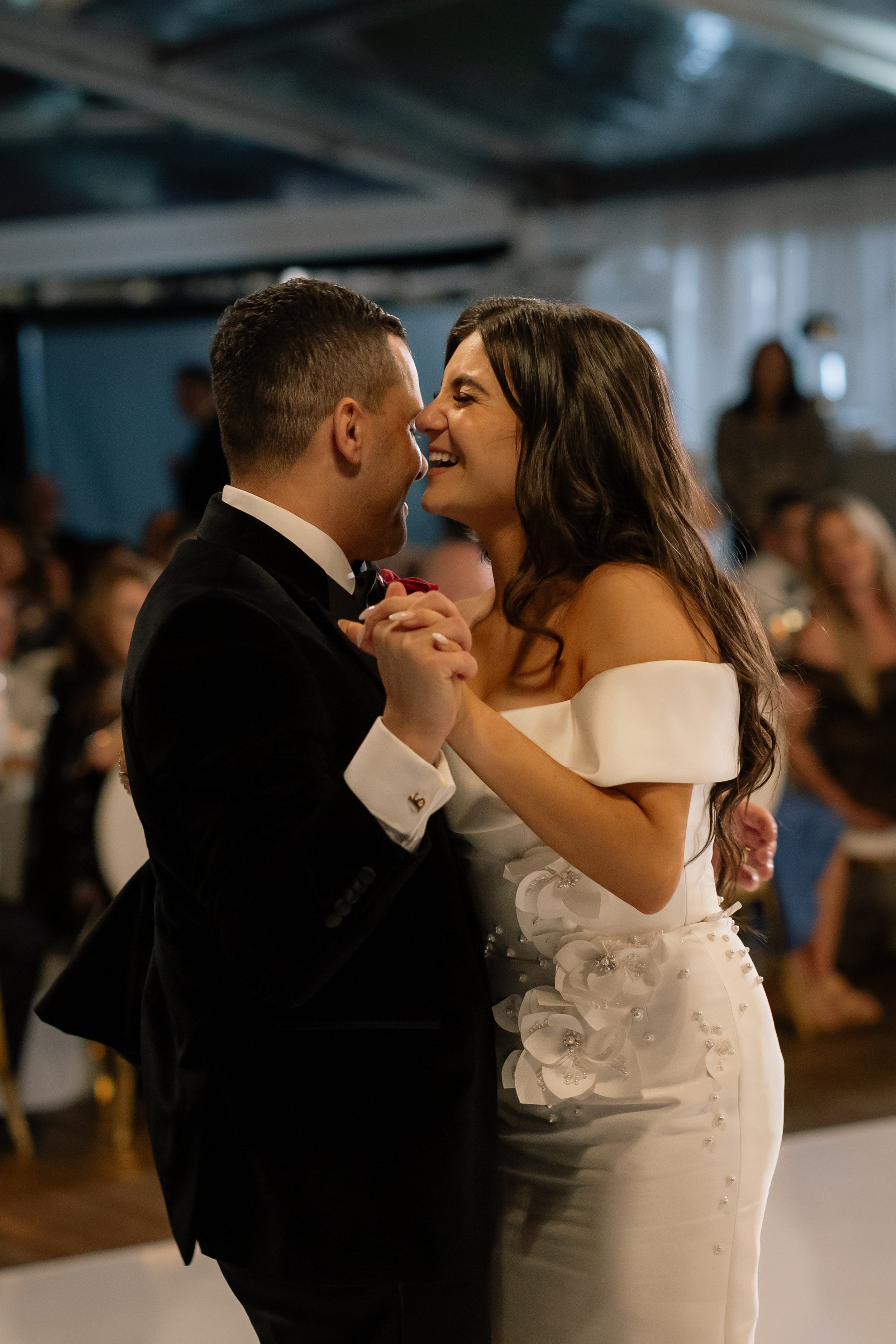 A laughing bride in an off-shoulder floral appliqué gown shares an intimate first dance with her groom at a Perth wedding reception