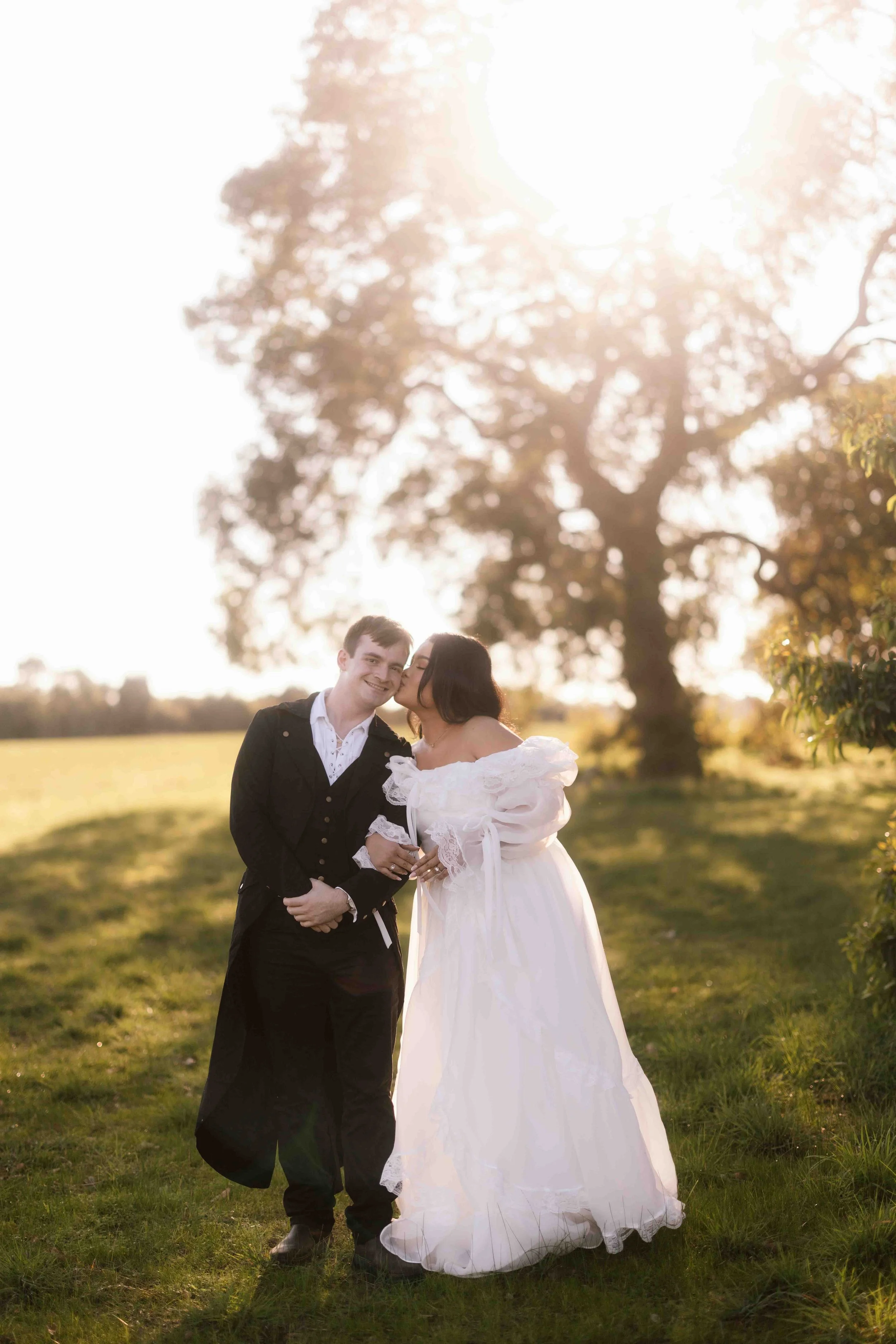 Bride in an off-shoulder ruffle gown kisses her groom's cheek during a romantic golden hour pre-wedding shoot at Perry's Padd