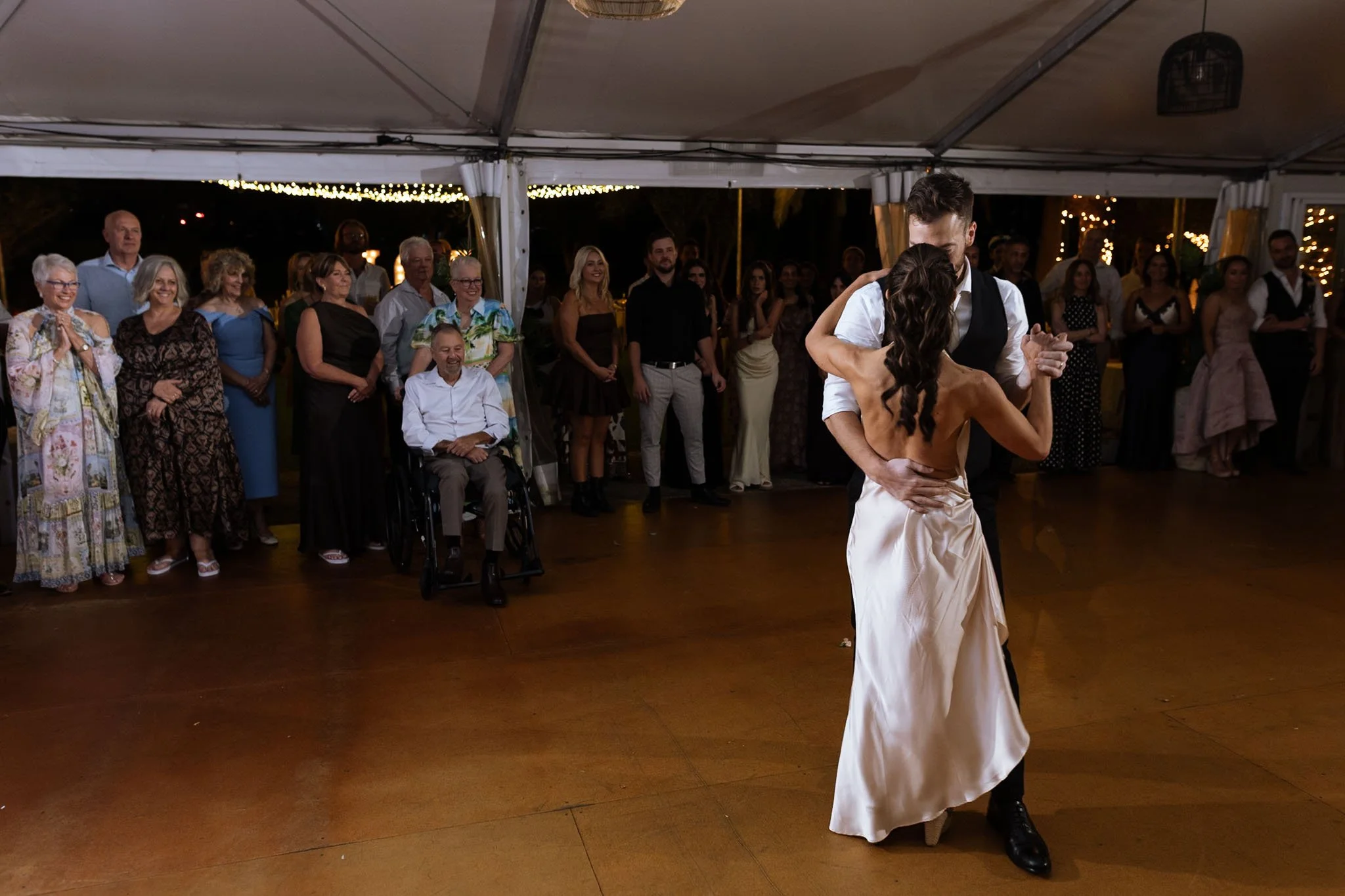Bride and groom sharing their first dance in a marquee reception tent at The Mallard Duck Swan Valley Perth, with family and friends watching warmly from the surrounding floor, photographed by James Di Stefano