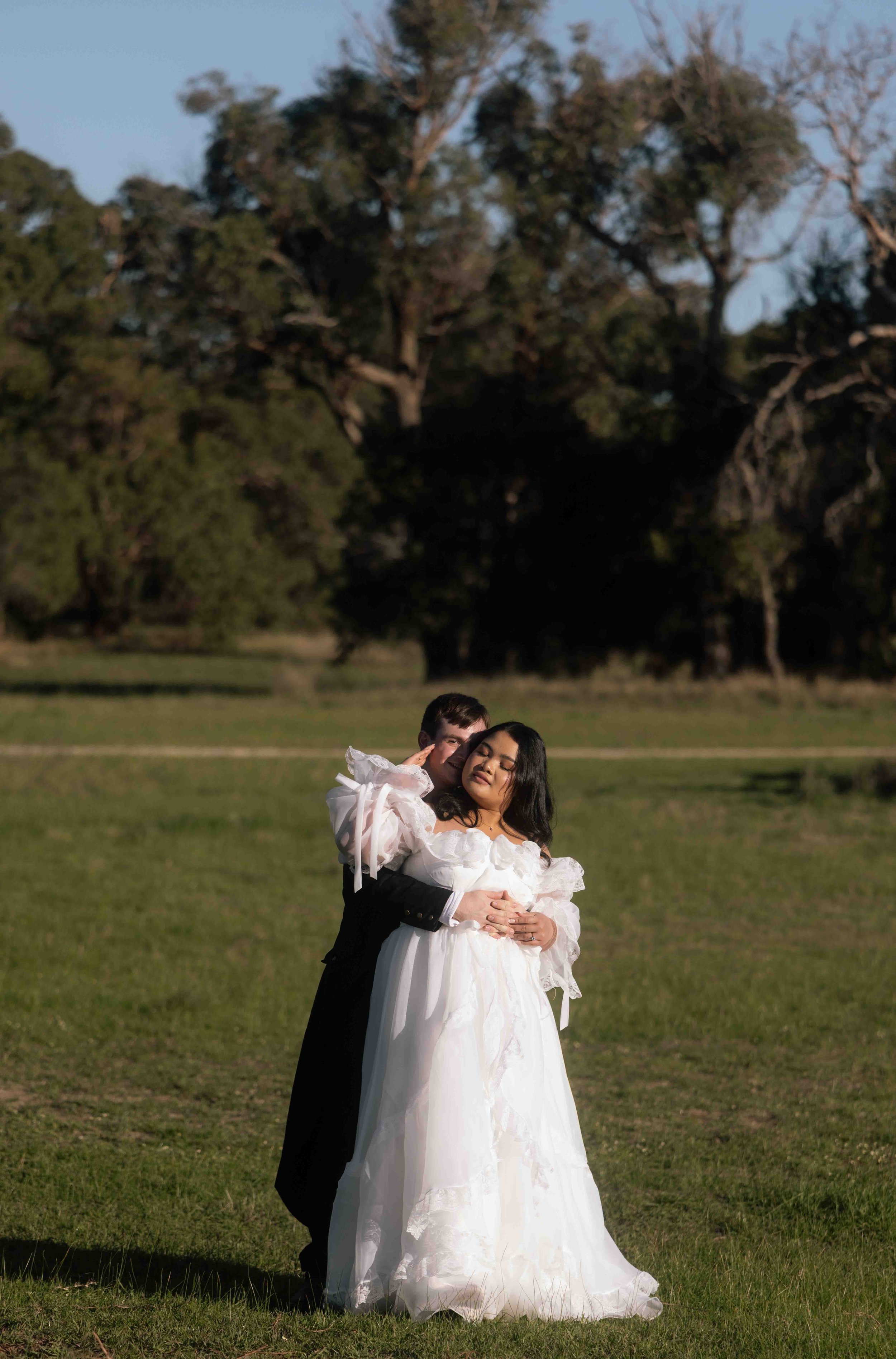 Groom wrapping his arms around his bride in a flowing ruffled gown at Perry's Paddock during a romantic golden-hour portrait