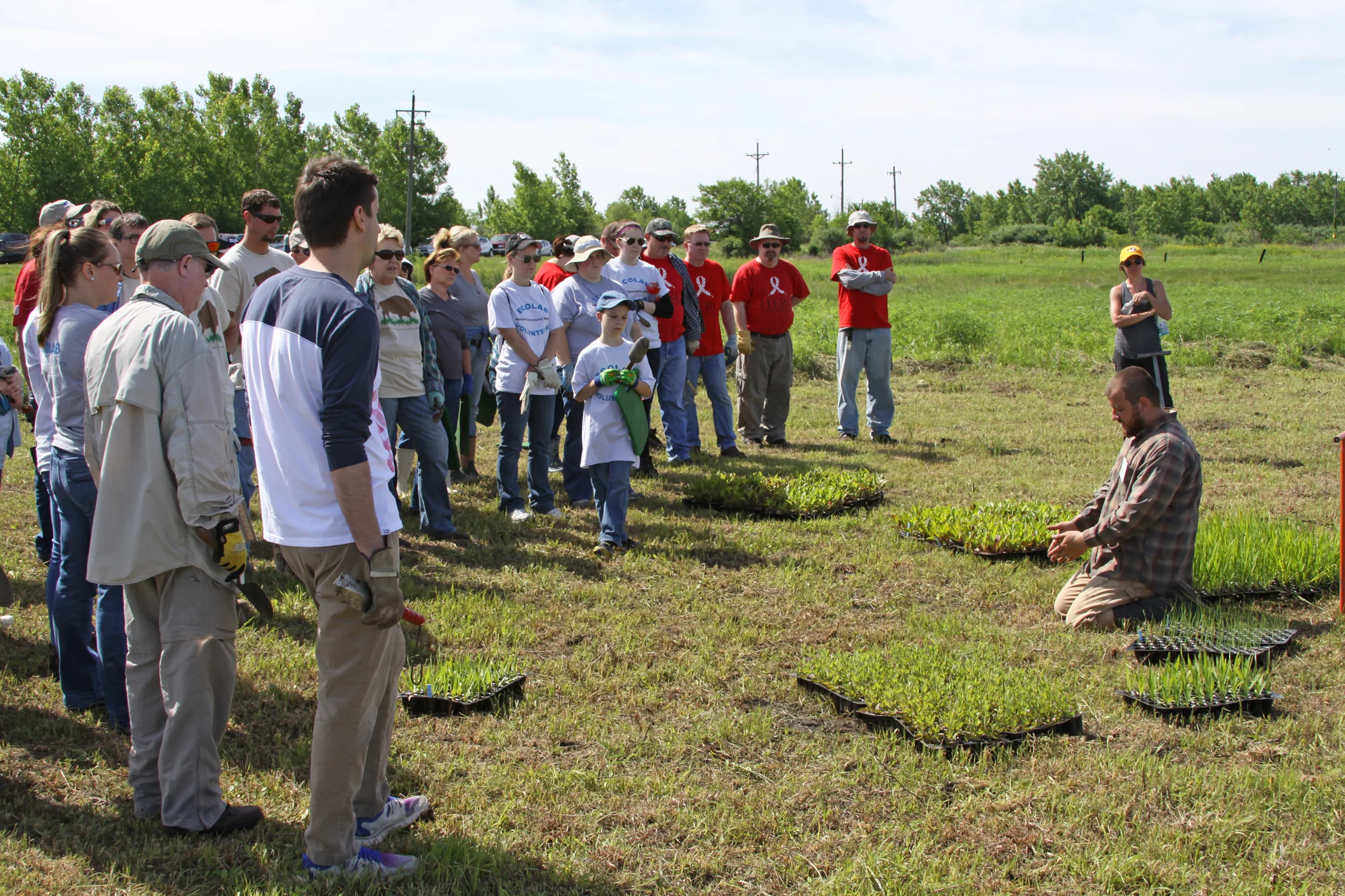 TWI Project Manager and Restoration Specialist Trevor Edmonson shows the group of corporate volunteers how to plant plugs.