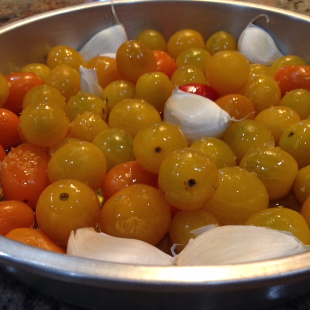 Farm fresh grape tomatoes nestled up against some garlic all sliding in olive oil