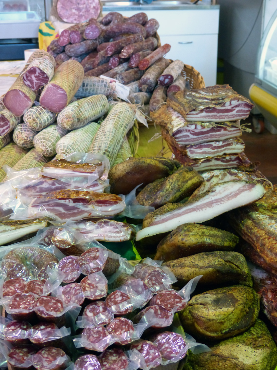 Dry cured meats in a small but fully packed local market Rome, Italy.