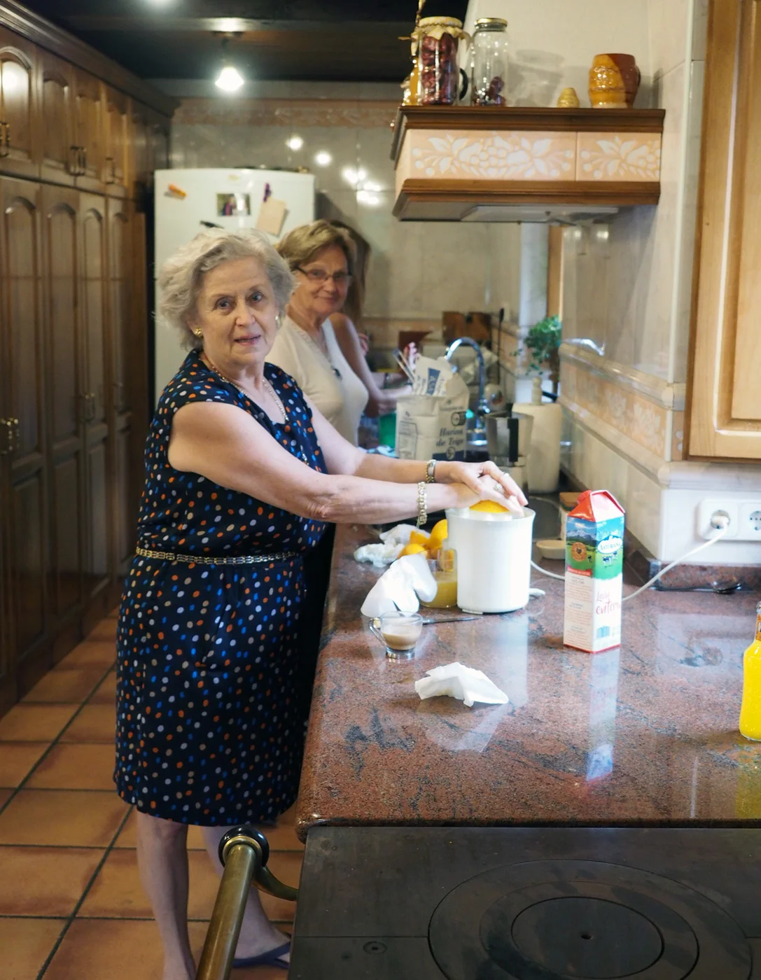 Maxi and Sofia making fresh orange juice while the sequillos are being made further down this long kitchen work space
