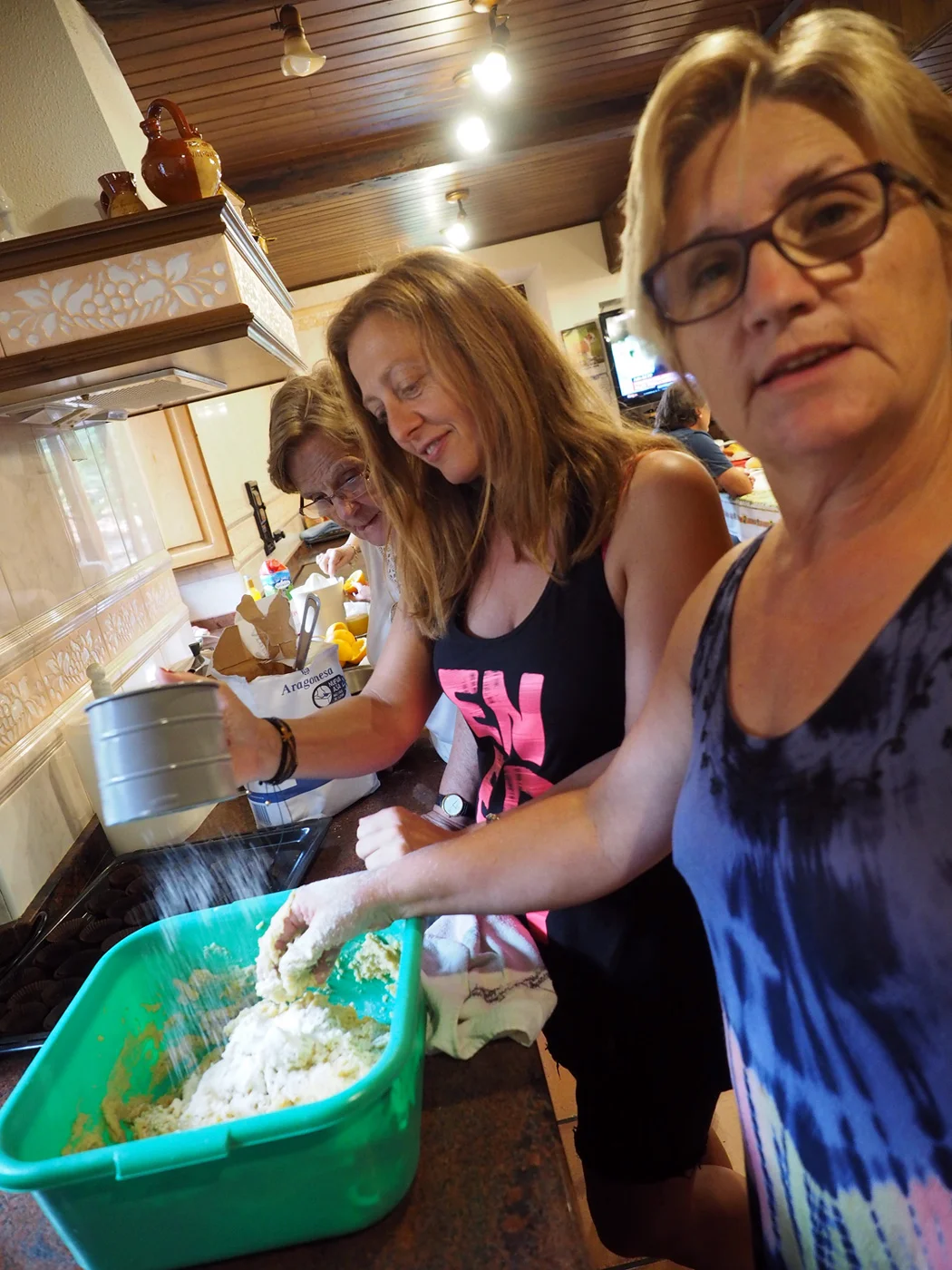 Sofia looking on as Maria sifts the flour and Marisa mixes the dough.