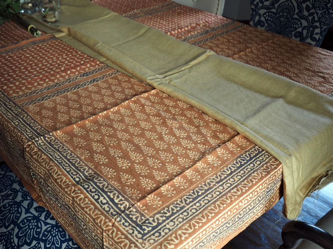 The runner has golden tones to it that will work well with the gold notes on the plates and chargers.