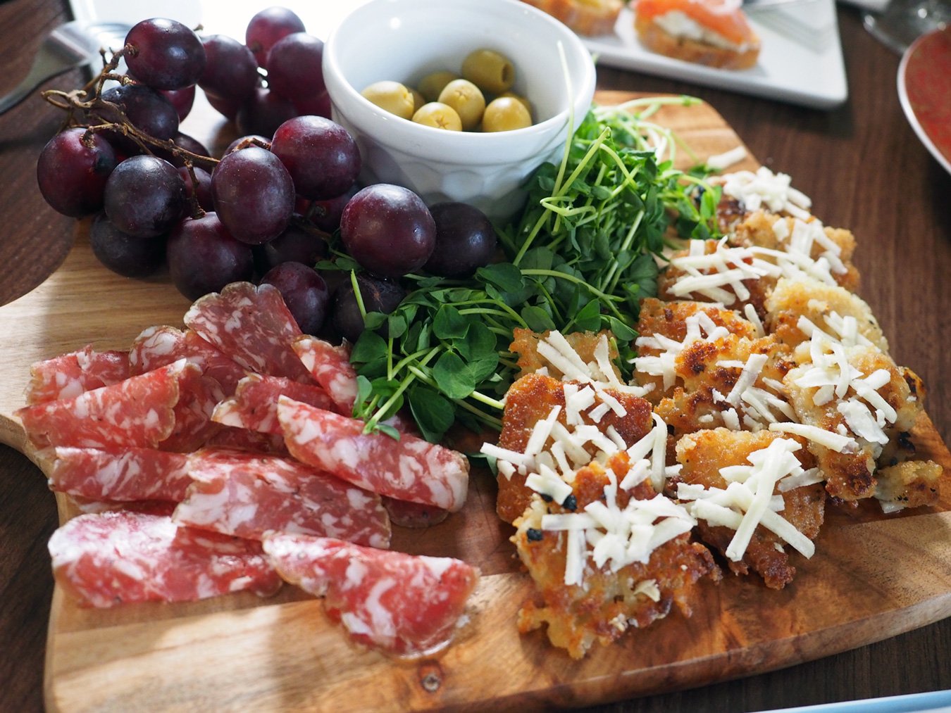 Rice Cakes with Parmesan, Salami, Pea Shoots, Grapes, Olives