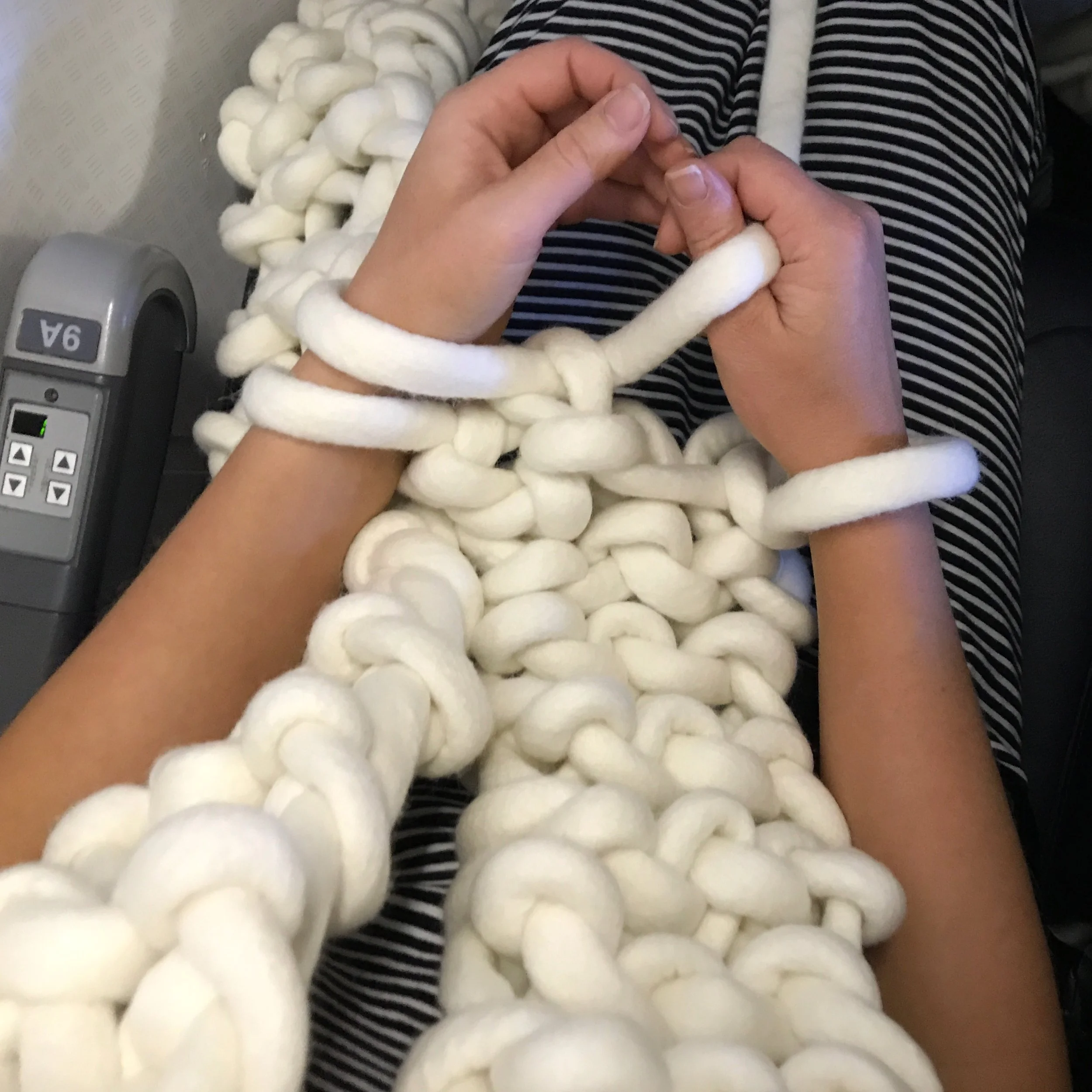 Clare Kearney of Woolly Element arm knits a chunky scarf with Little Dandelion, K1S1 yarn, 100% merino wool, on a flight back to Dallas.