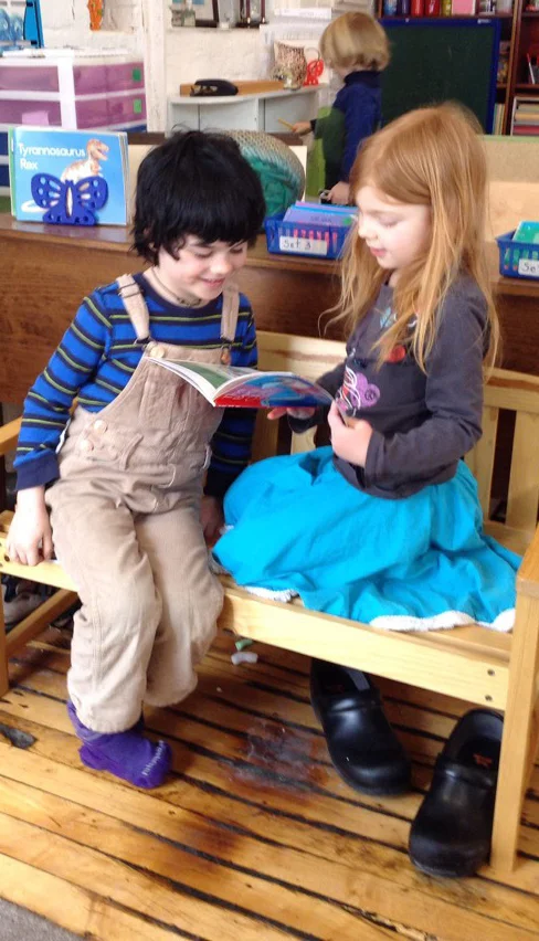 Two students enjoy reading a book together.