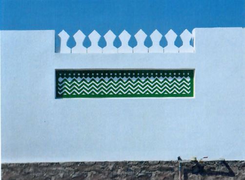  An image of a remodelled wall that is painted white, and that incorporates a stone base, crenellations at its top, and a small mural with a wave-like theme 