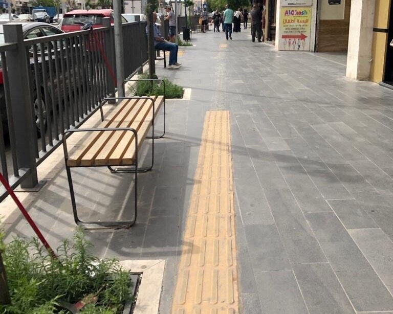  A tactile navigational strip that has been installed too closely to a planting bed and a bench, making it difficult to use by the visually impaired as they may bump into those sitting on the bench or step into the planting bed. Also, as may be seen 
