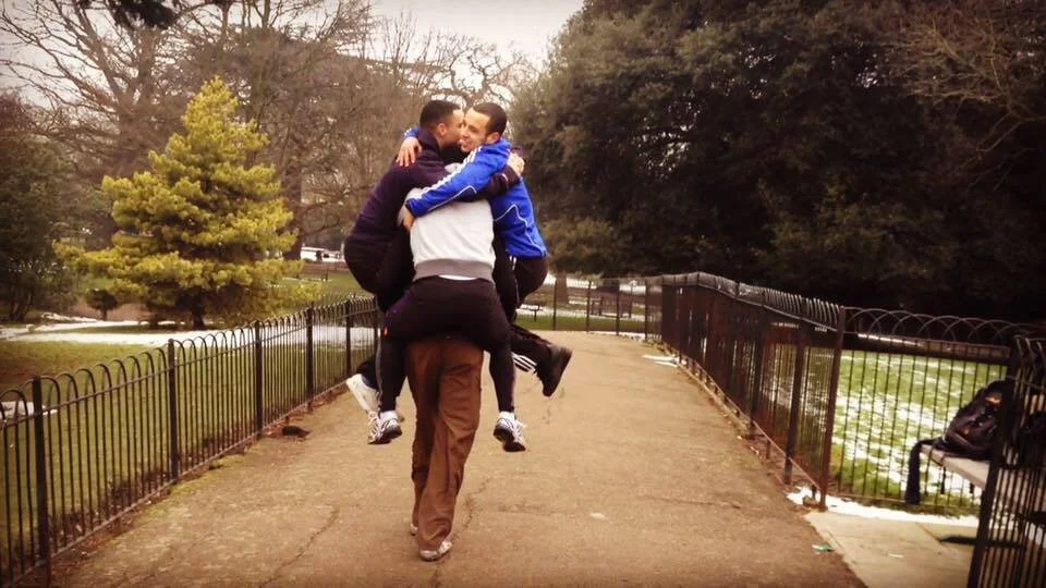 Darryl Edwards carrying three adults during an advanced multi-person piggy-back challenge in a park