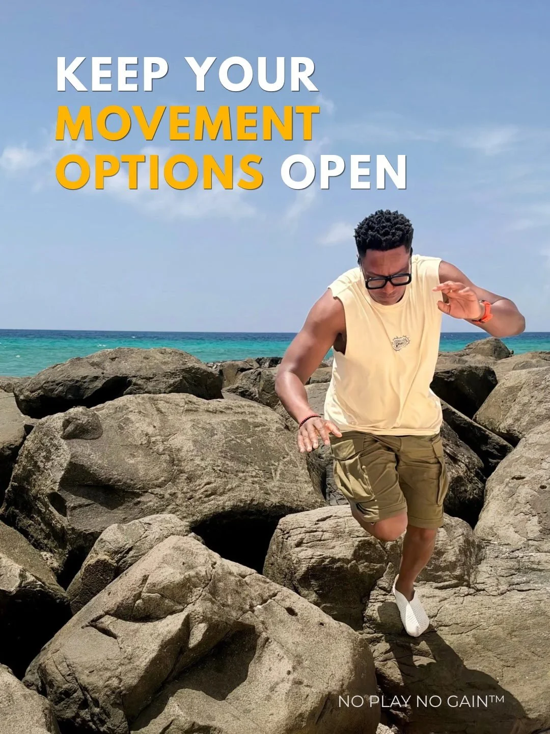 Darryl Edwards balances as he steps between rocks beside the sea.