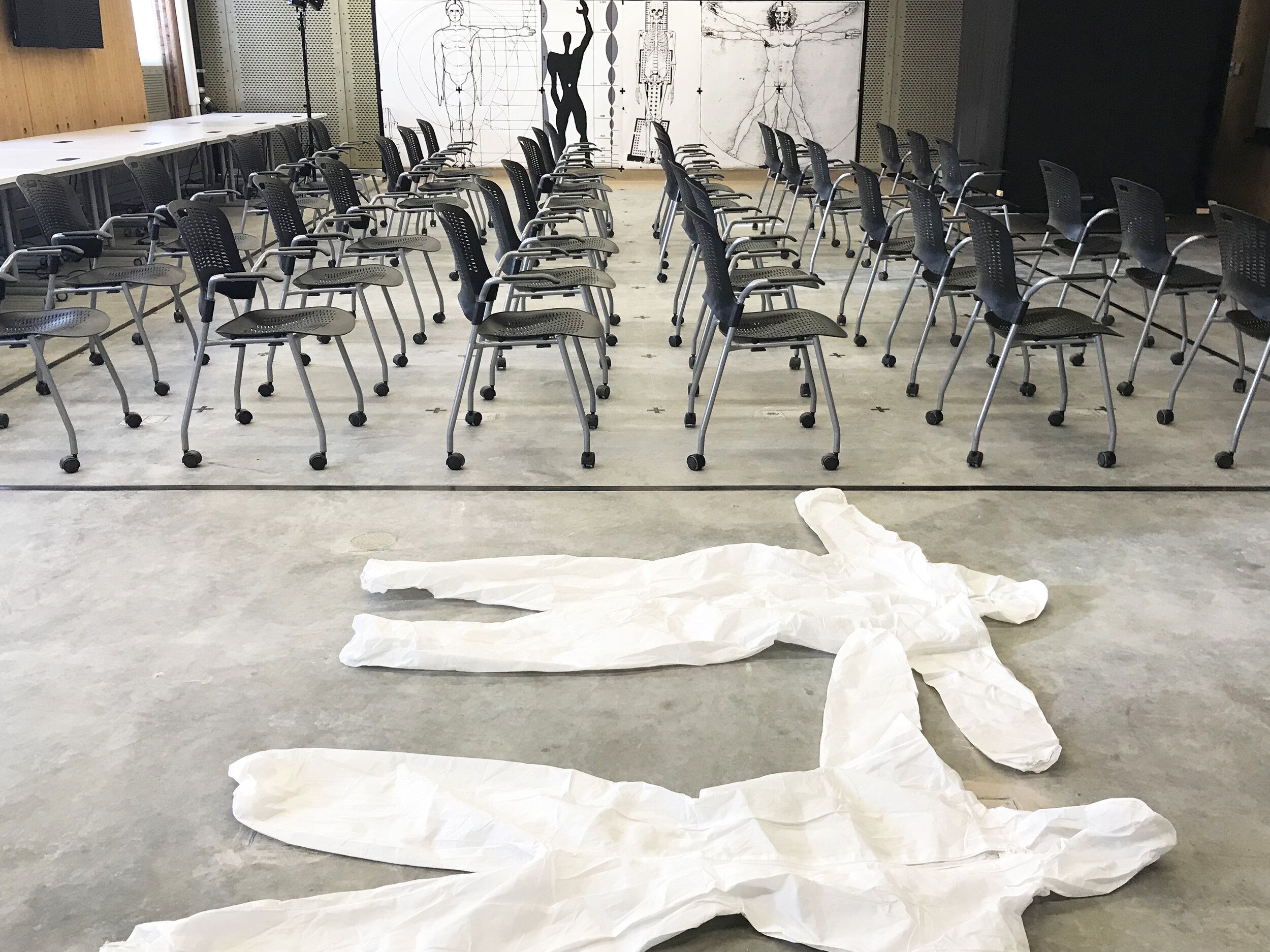  Seen here, just hours before the performance, is the rigorous seating ordinance at the centre of the room and, beyond that, the reproductions. In the foreground, the authors’ coveralls lie still,  awaiting critical collaboration. Photograph by Braed