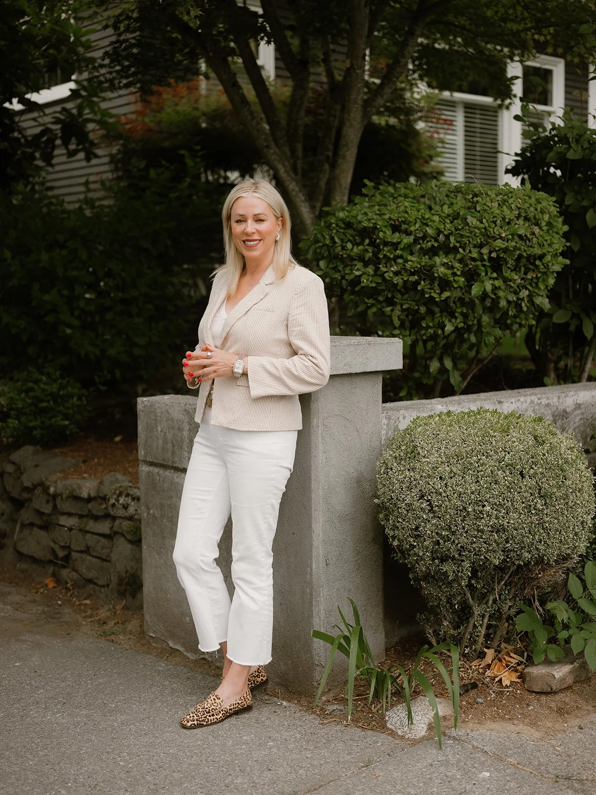 blond woman standing in front of house wearing white pants and tan blazer in seattle washington