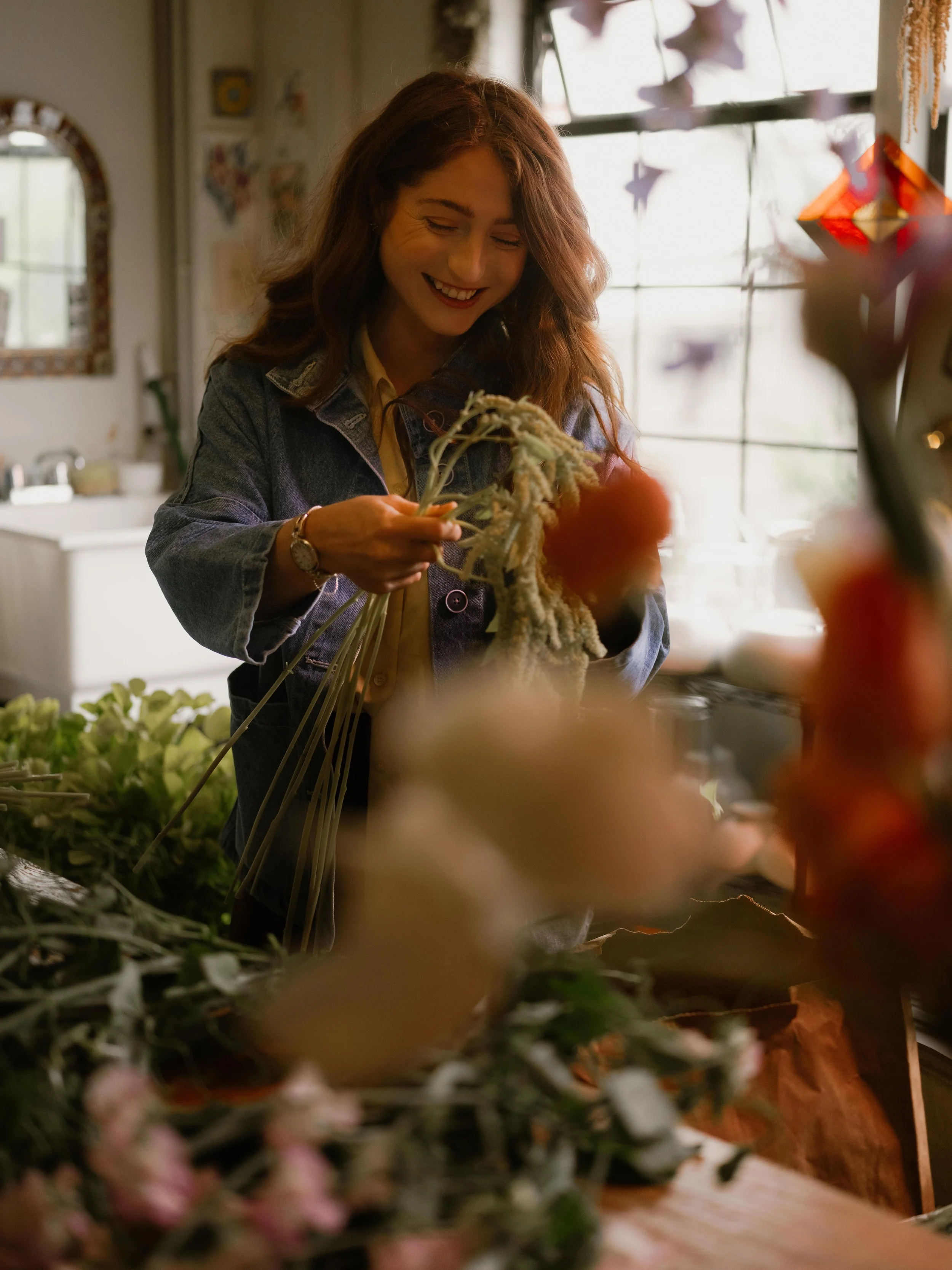 woman arranging flowers at table in her studio in seattle washington