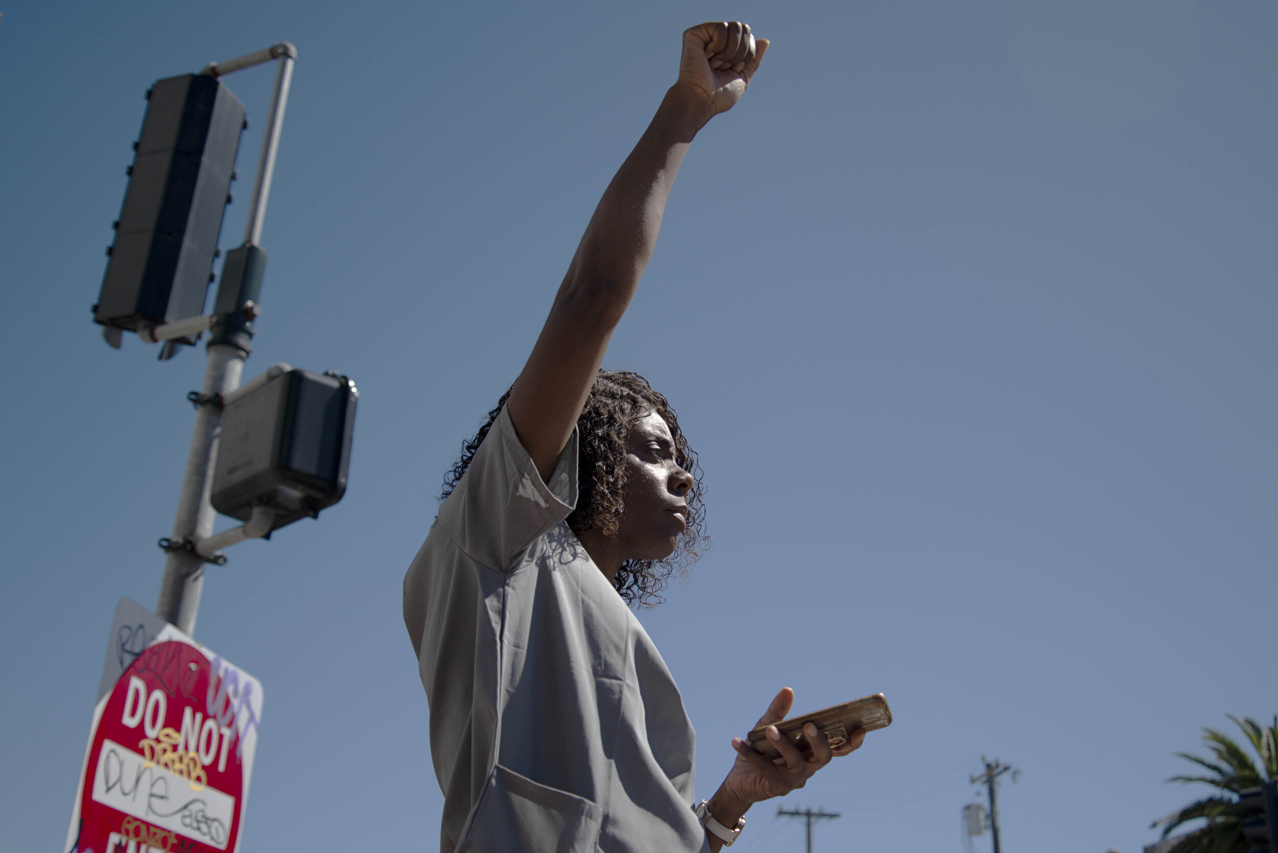  Jahmela Rowland raises a fist in solidarity with police brutality demonstrators passing by in San Francisco, Ca. on June 13, 2020.  