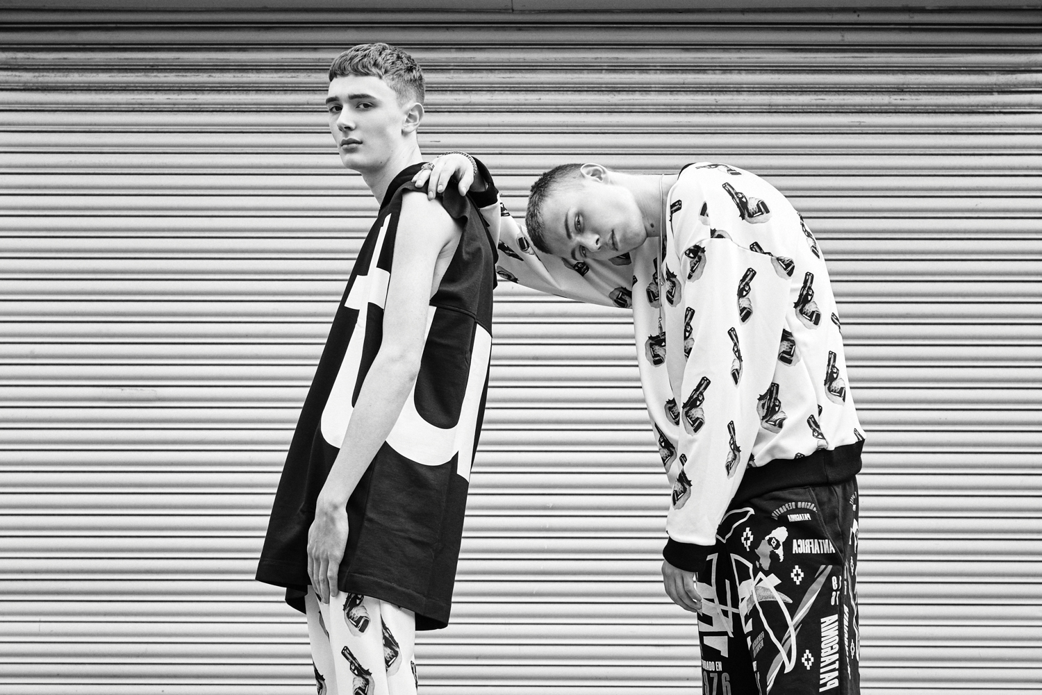 Left Model: Sleeveless Hood T-shirt - ÉTUDES Trouser - SULDN. Right Model: Top - SULDN, Short Pants - Marcelo Burlon Jewellery - Model’s own.