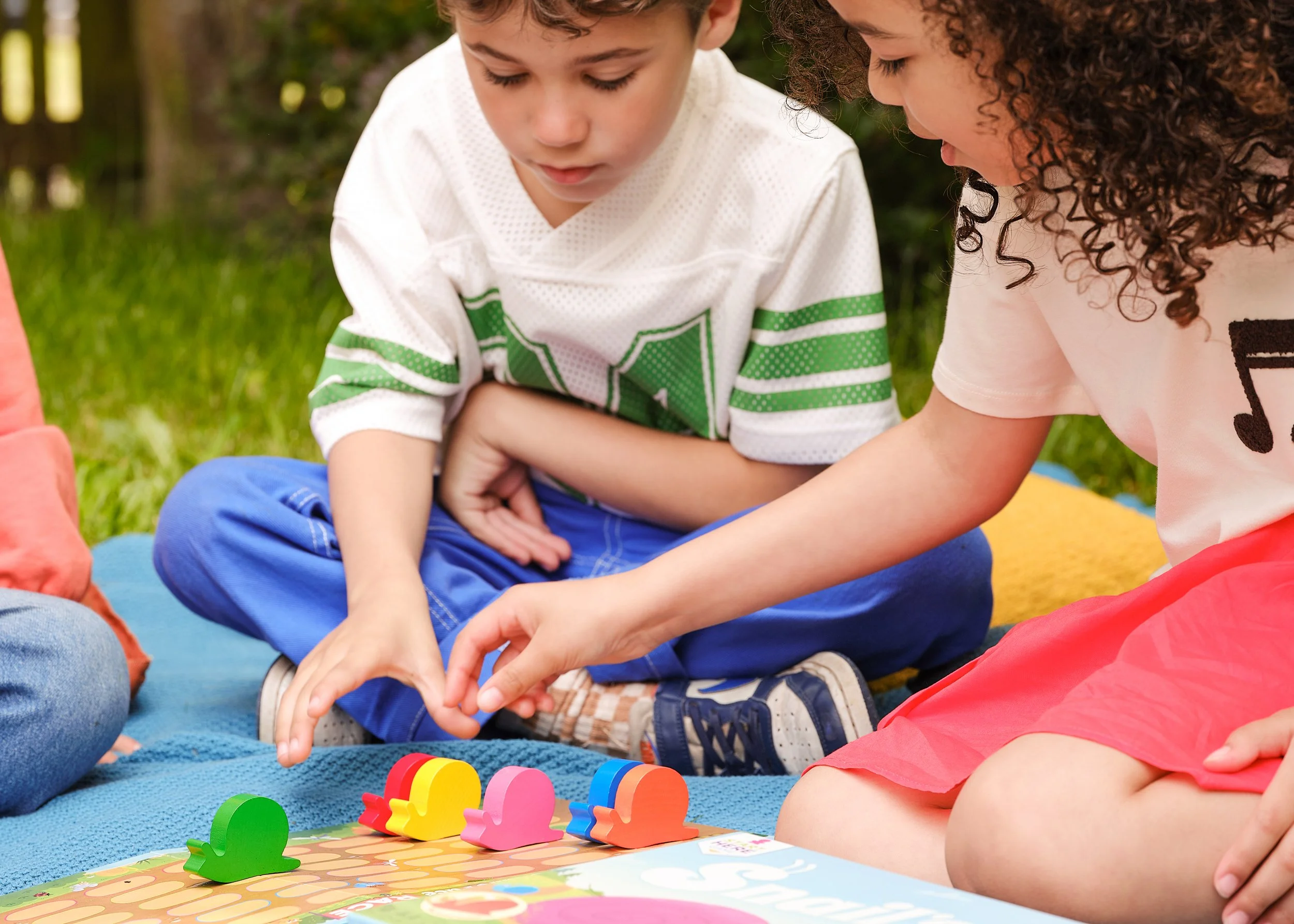 Kids playing boardgames on a picnic blanket
