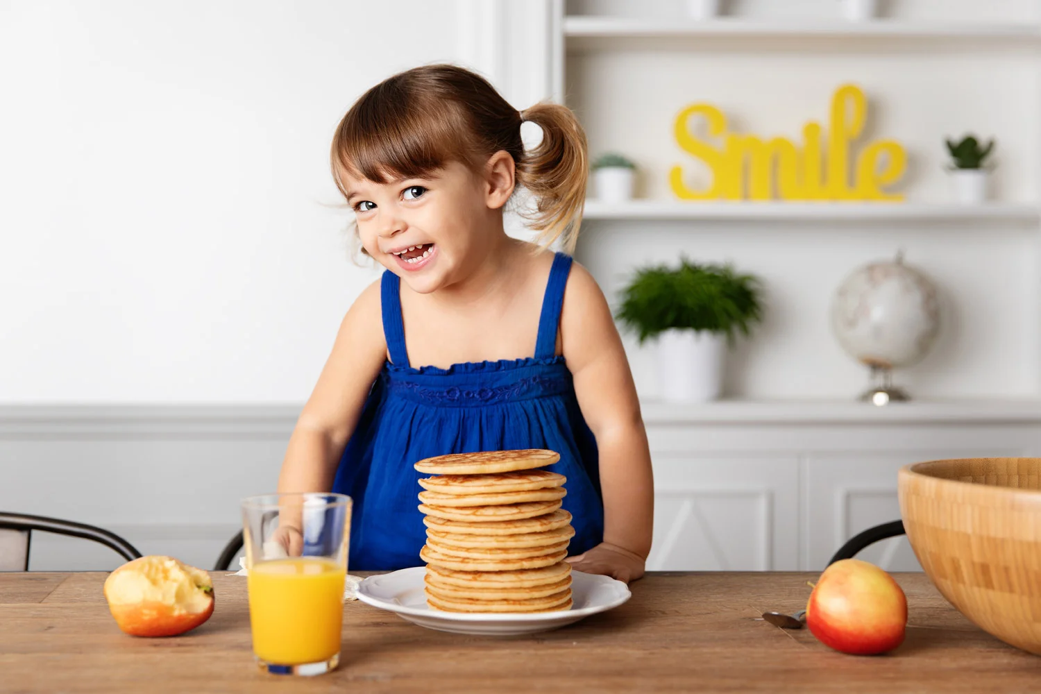 Funny toddler smiling next to stack of pancakes by advertising kids photographer Lisa Tichane