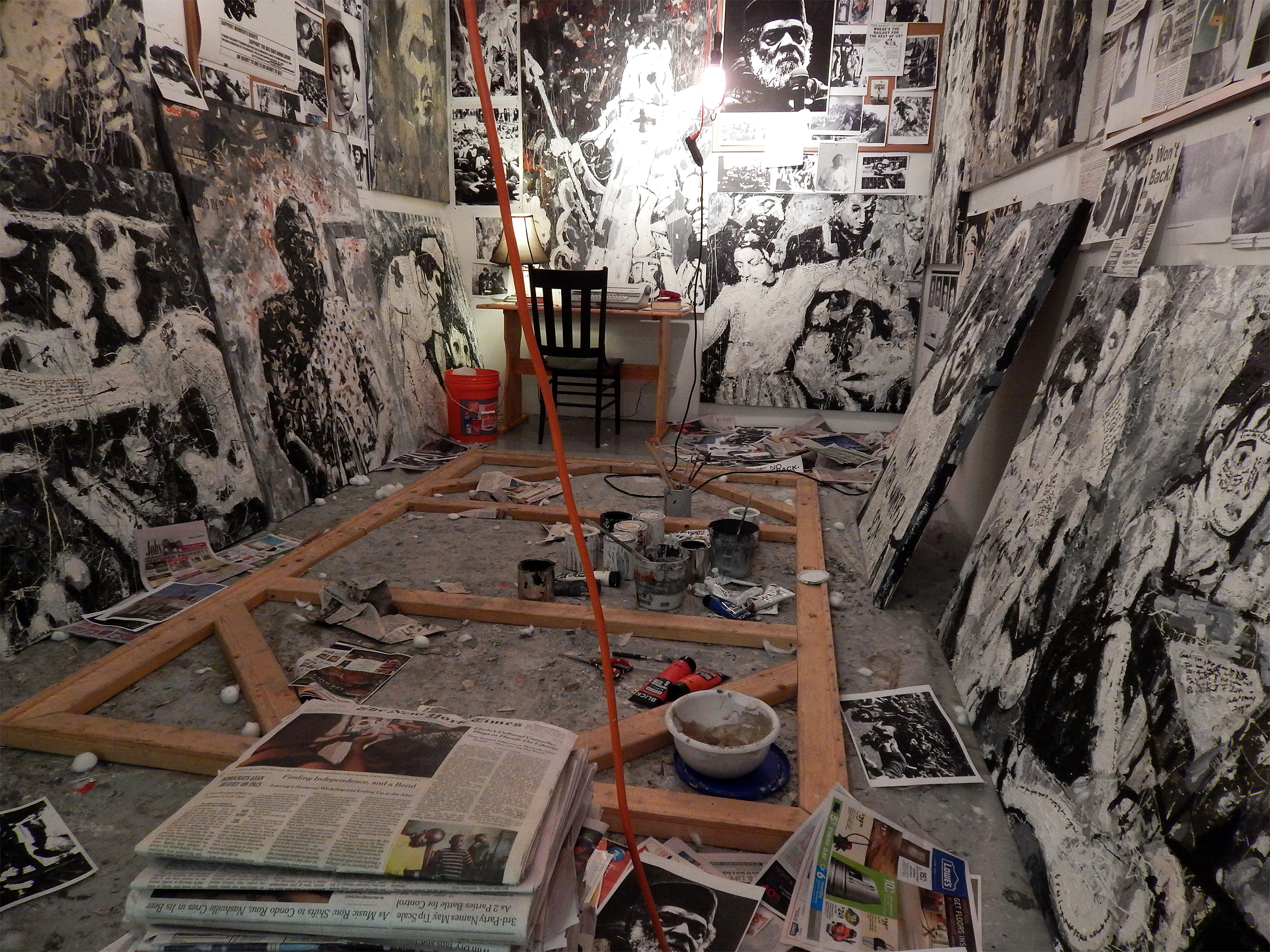 A Painter of Our Time (installation at the Sam Fox "Safe Space") Acrylic, cotton, concrete, newspaper, ash and Sharpie on canvas with photographs, wood, newspaper, found objects, hanging lights (2014).