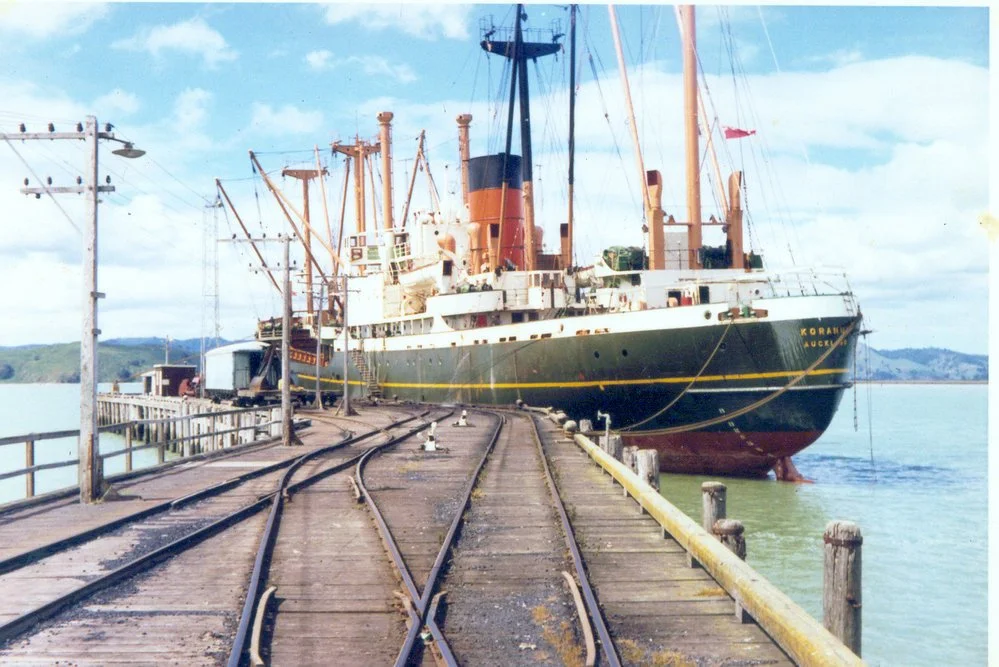 James Russ Portland wharf Large steamship docked at a pier with railway tracks, overhead electrical lines, and a rural landscape in the background.
