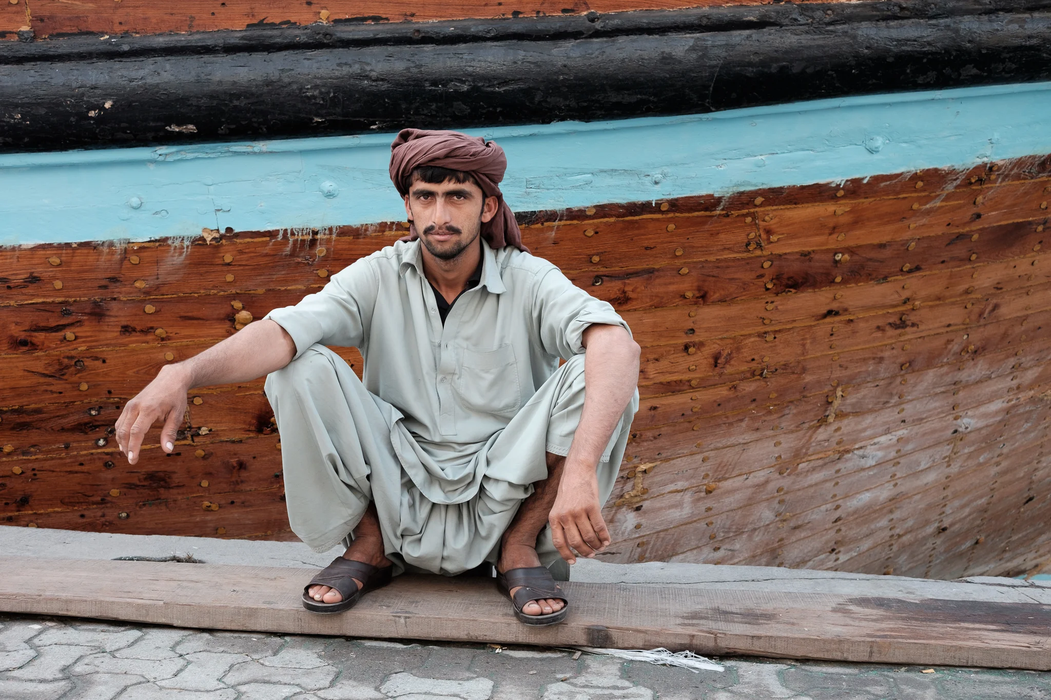 Young Pakastani man taking a break from loading goods on to a Cargo ship heading for Iran