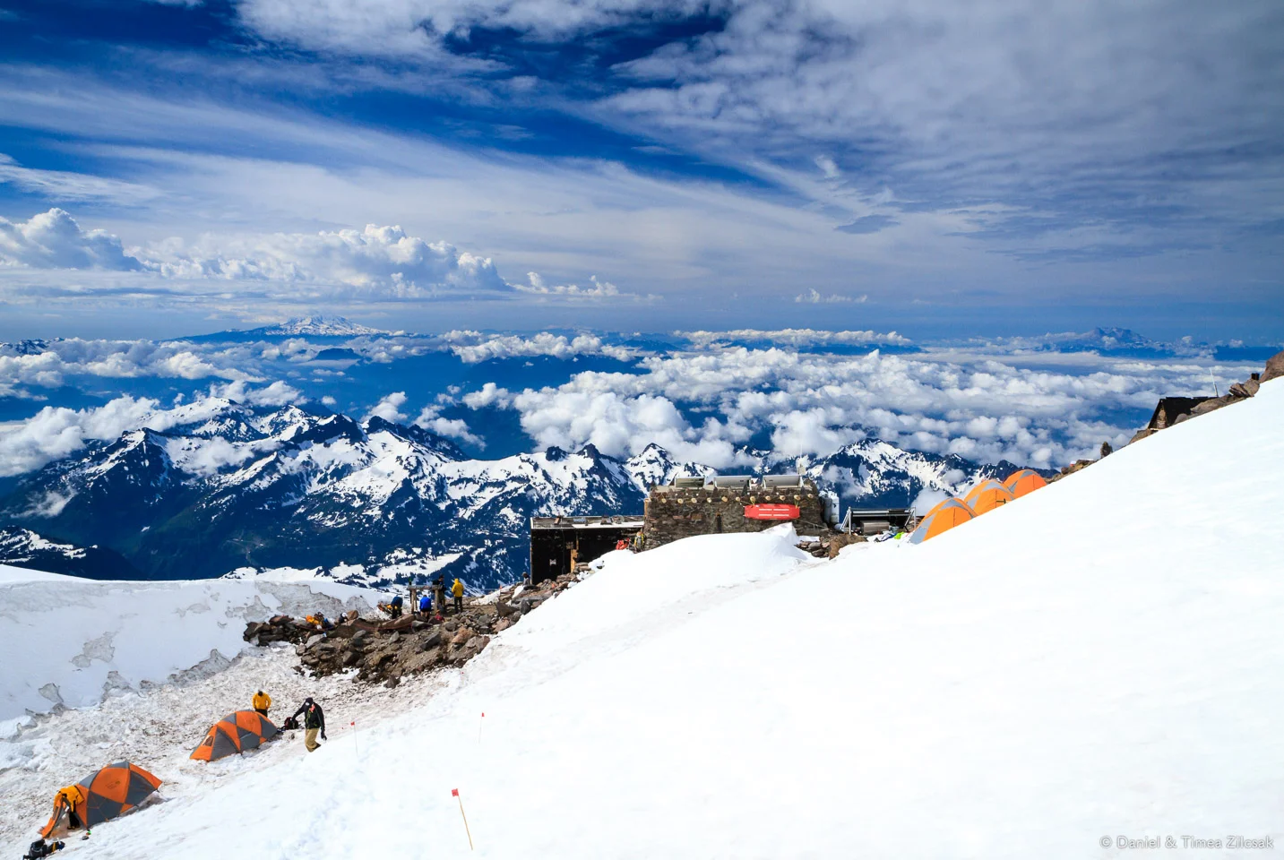 View from Camp Muir: the main shelter/hut and climbers' tents with Mount Adams right below the clouds