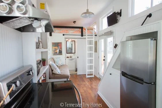 Tall fridge under staircase with storage. Music City Tiny House