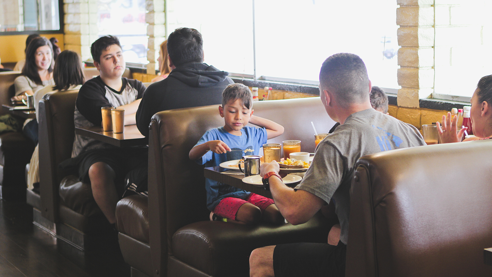 Young boy with father sitting in booth sharing a meal inside