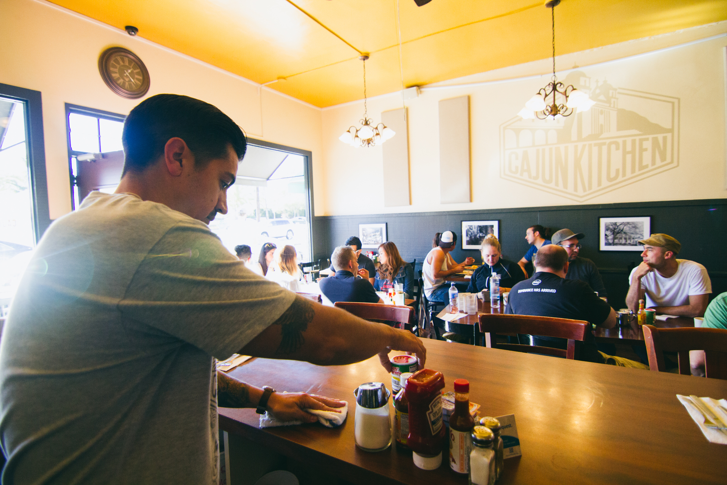 Server wiping bar down while customers eat at tables