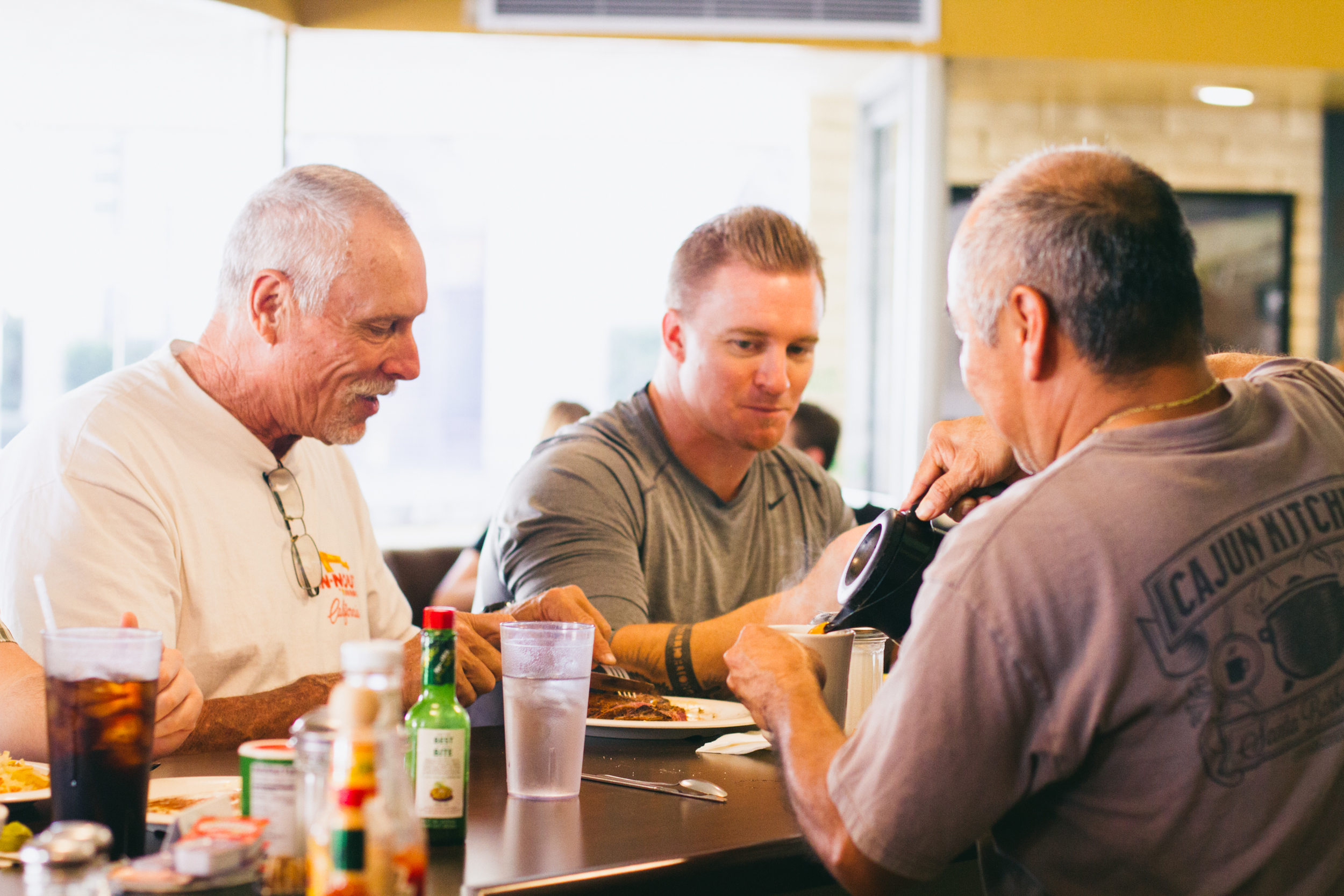 men enjoying food while being served coffee