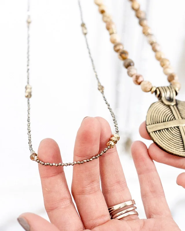 The Pyrite Shine Necklace features tiny faceted pyrite stones divided by shimmering Czech crystals. The Jasper Medallion Necklace is a long faceted jasper gemstone necklace, featuring czech crystals and a bronze pendant. 