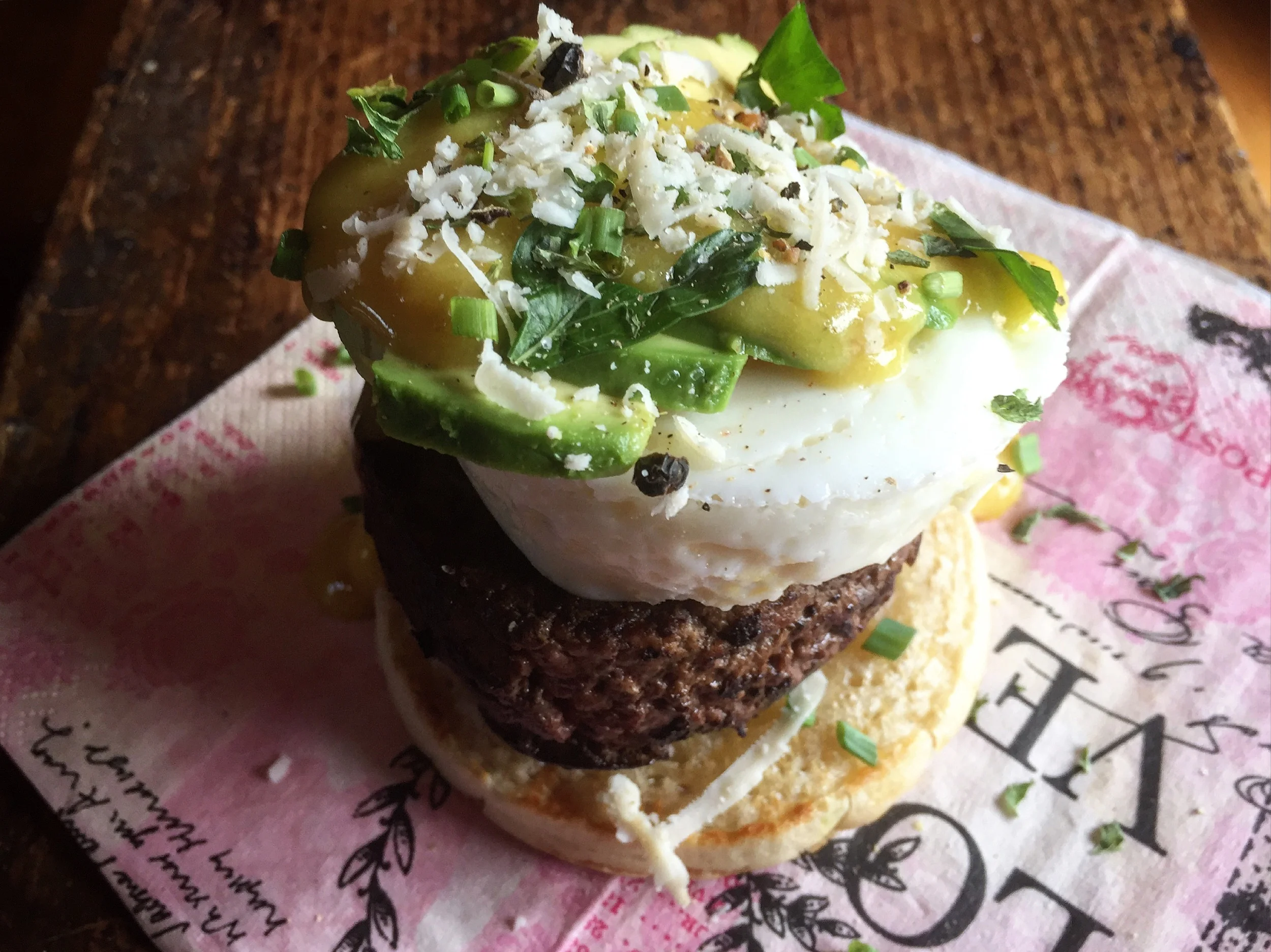 "Kobe-Wagyu Sirloin Burger Eggs Benedict" with "Avocado" and "Peppered Asiago" on top of a buttered & toasted "English Crumpet"