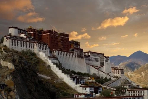 "The Potala Palace, home of the Dalai Lama, stands at an angle on a hilltop during a beautiful sunset in Lhasa, Tibet"