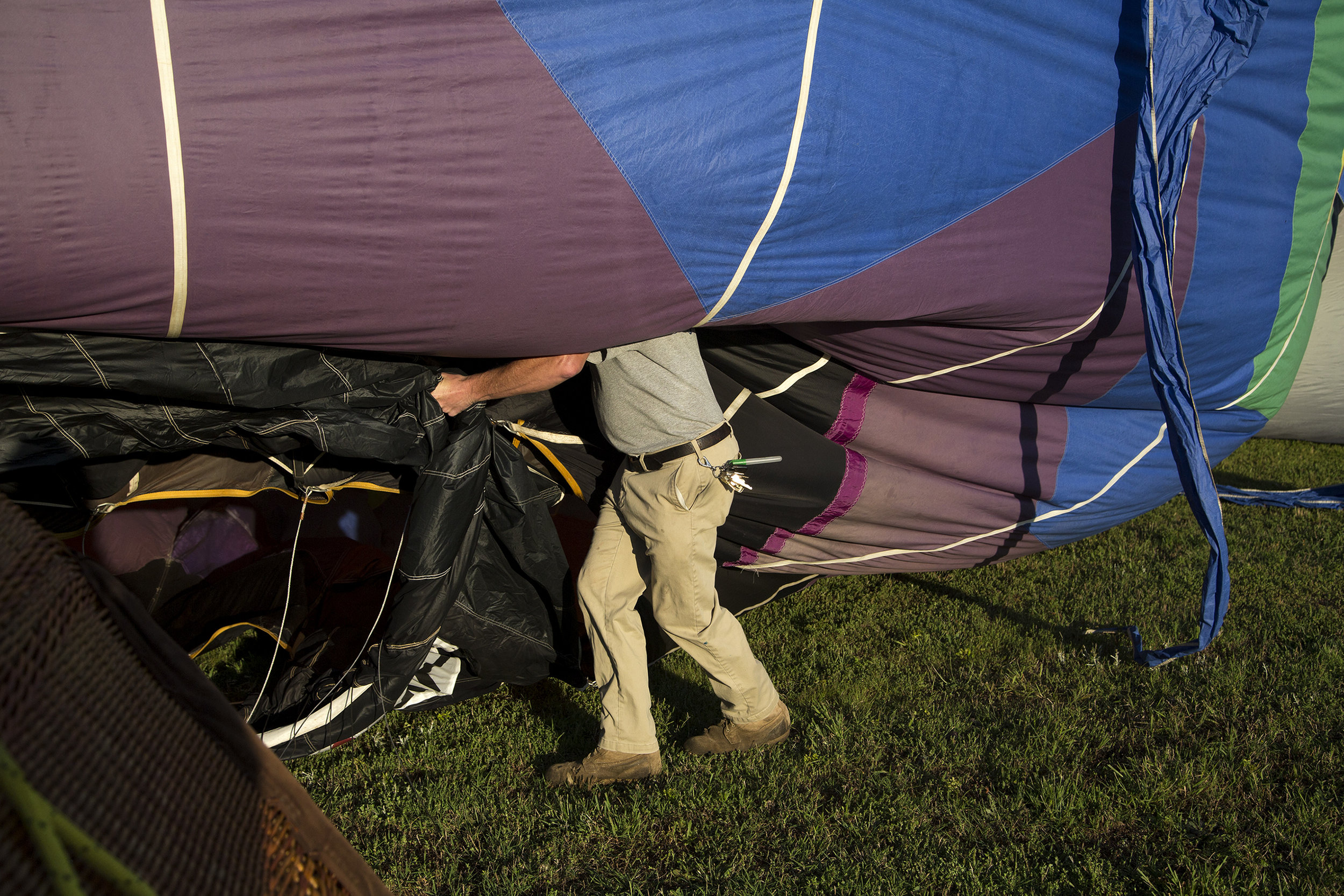  Luke Mason, a ground crew chief for Coastal Balloons, holds the opening of the Spectrum hot air balloon as it inflates before an early morning flight on June 4, 2019. 