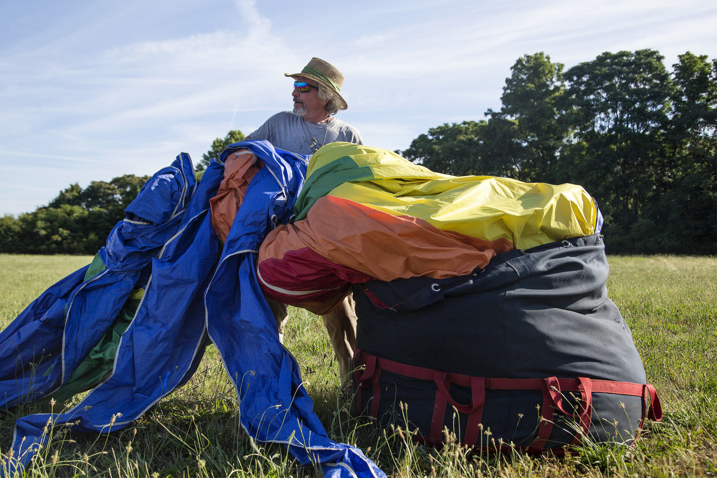  Luke Mason, a ground crew chief for Coastal Balloons, puts the Spectrum hot air balloon into its storage bag after a morning flight over Smithfield on June 4, 2019. 