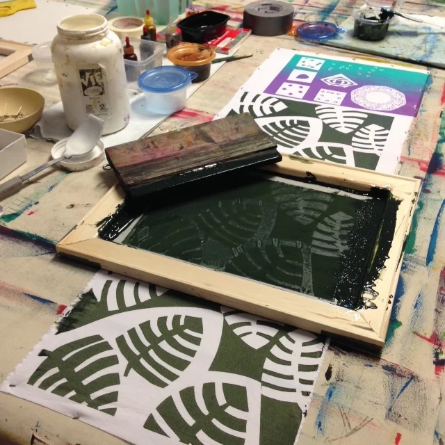 Silk screening with paper cut out patterns.